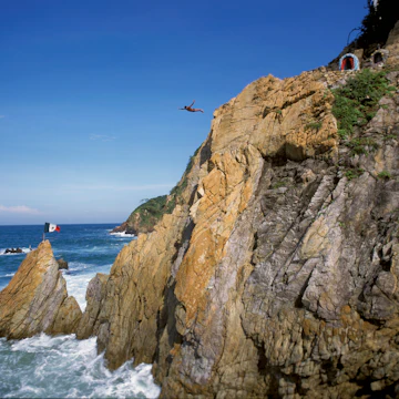 Mexico: Acapulco: A La Quebrada cliff diver leaps into the Pacific Ocean, along the Mexican Riviera