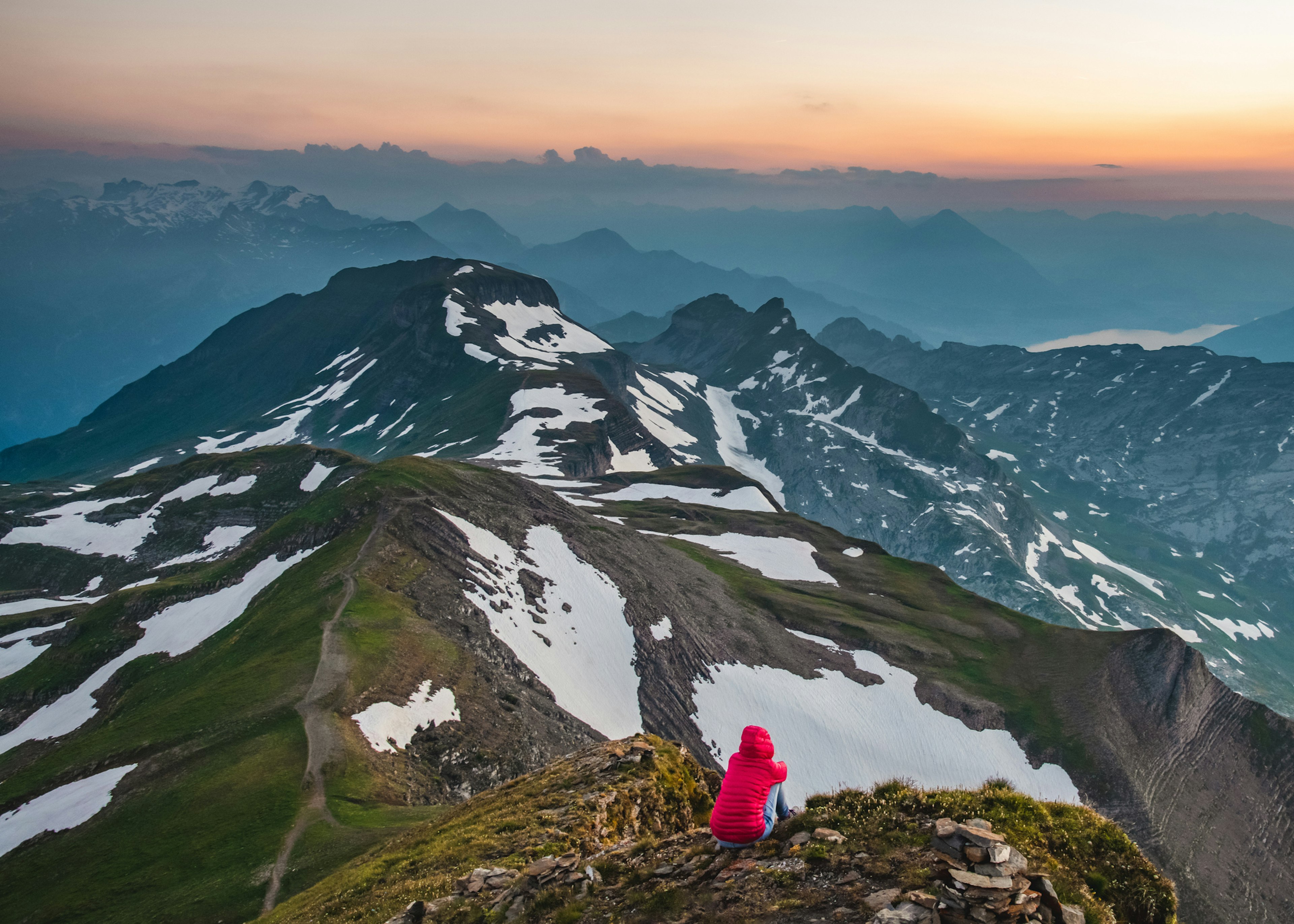 Lone hiker watches the sunset over a lake in a mountainous region