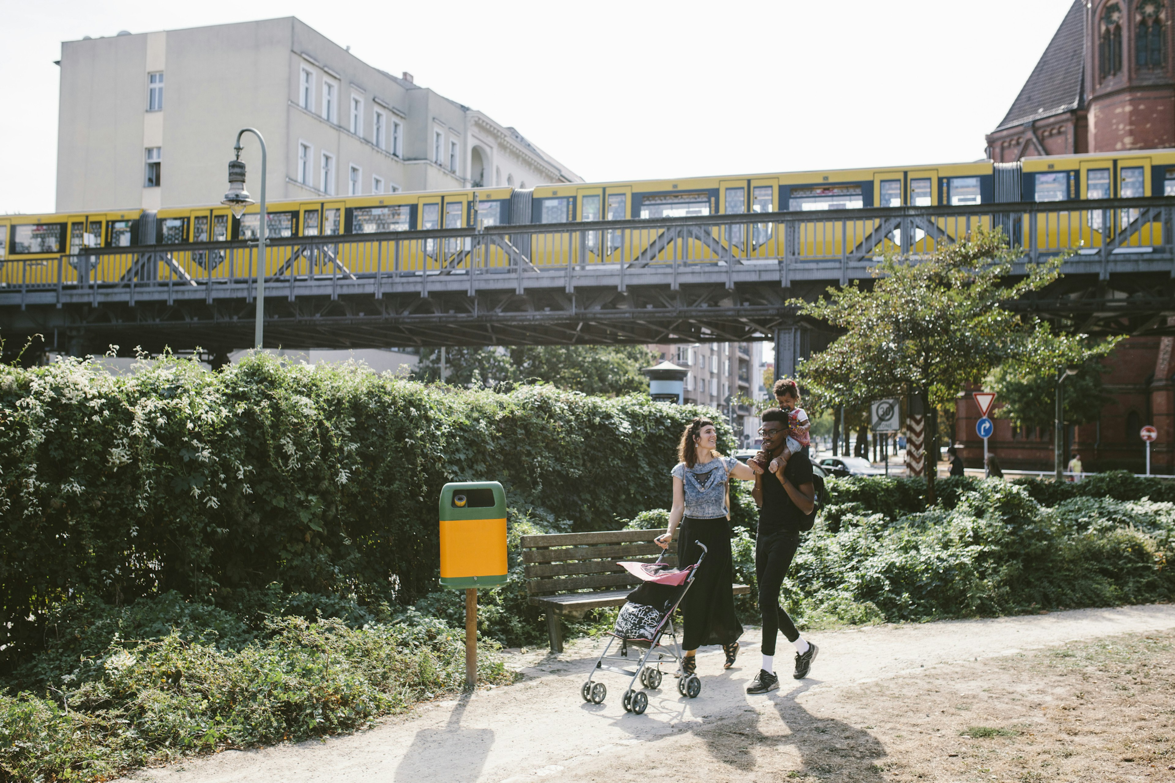 A family of mum, dad and small child walk along a path in a German town with a stroller