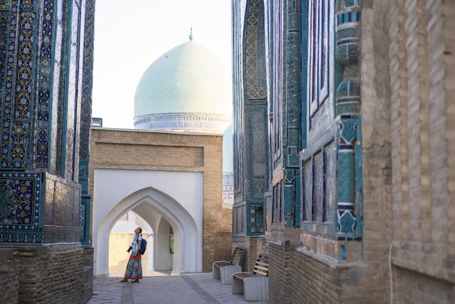 Senior woman on the path between memorial buildings of Shakhi Zinda Mausoleum which is memorial complex of Islamic architecture from 9 to 12.