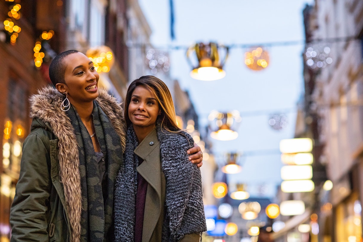 Two black women embracing as they walk down the street in Amsterdam