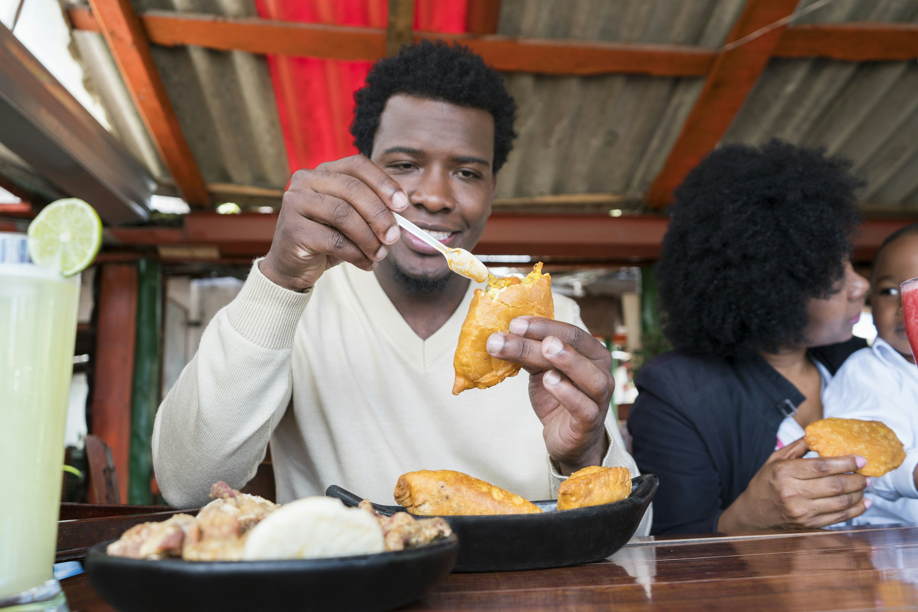 A man sits at a table in a restaurant putting sauce on a triangle-shaped pastry