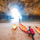 Father and son together paddling in kayak
1212351713
Father and son pushing a kayak into the water within a cave in the Algarve