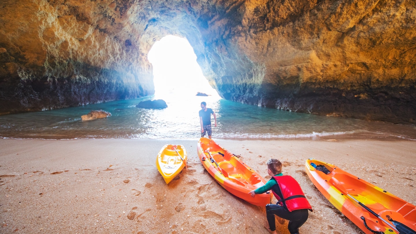 Father and son together paddling in kayak
1212351713
Father and son pushing a kayak into the water within a cave in the Algarve