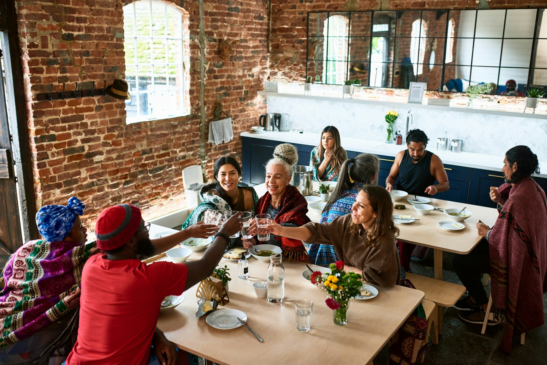 A group of friends sat around a large table in a restaurant share a toast 