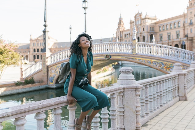 Happy woman sitting on railing at Plaza De Espana, Seville, Spain - stock photo
