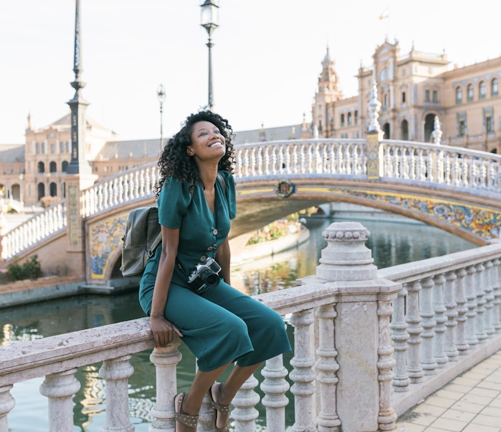 Happy woman sitting on railing at Plaza De Espana, Seville, Spain - stock photo