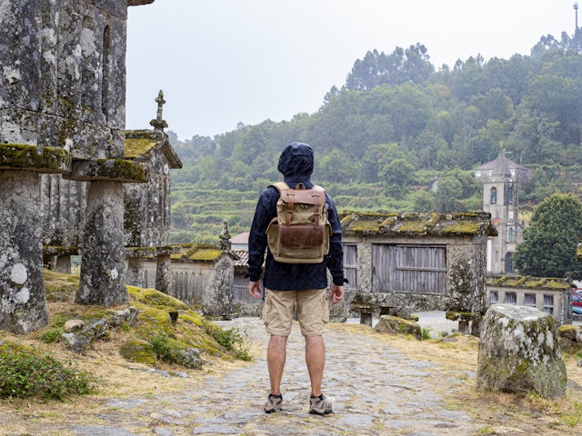 Man on his back looking at the historic stone barns in the town of Lindoso in Portugal as it rains.