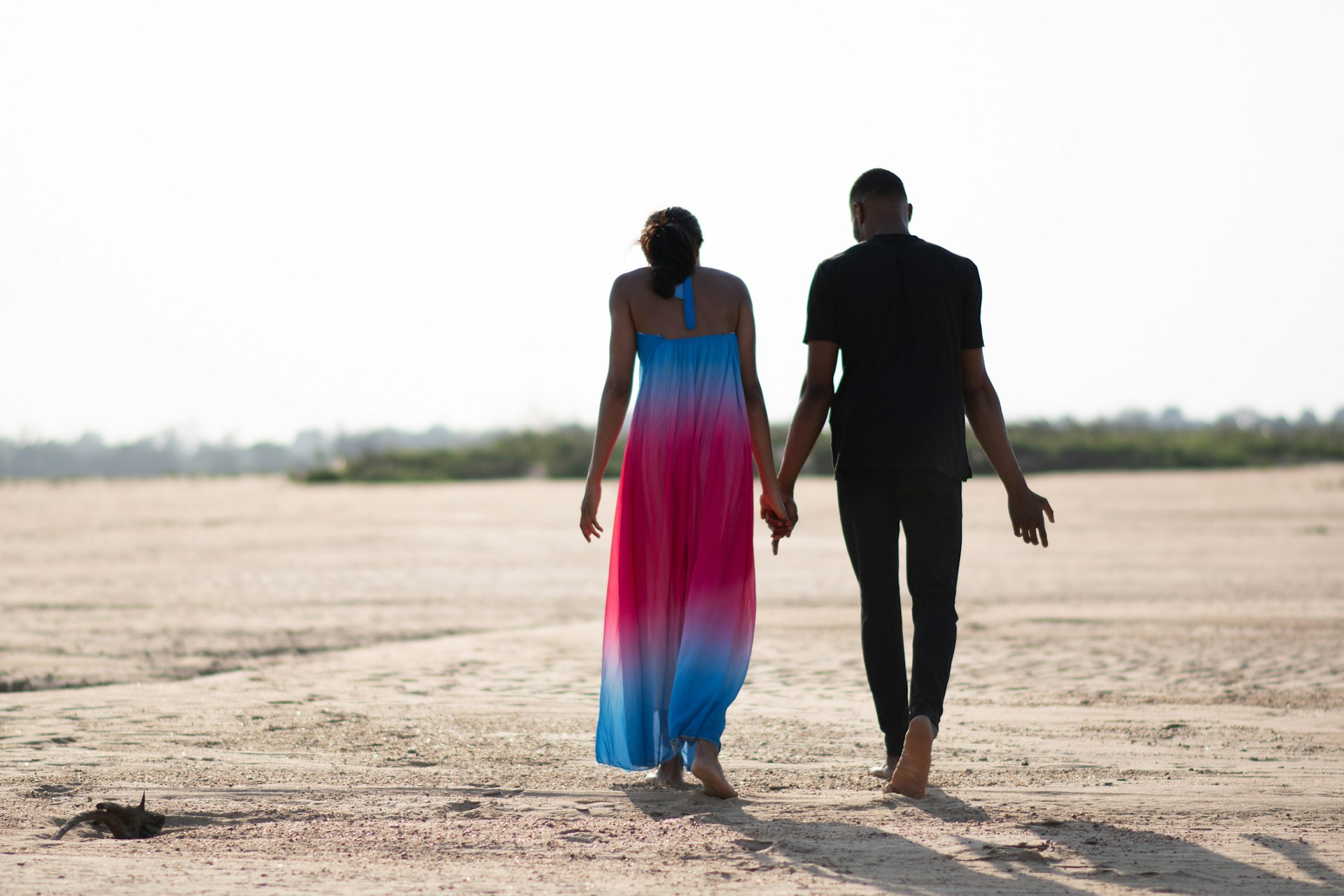 A couple walking barefoot on a beach in Nigeria