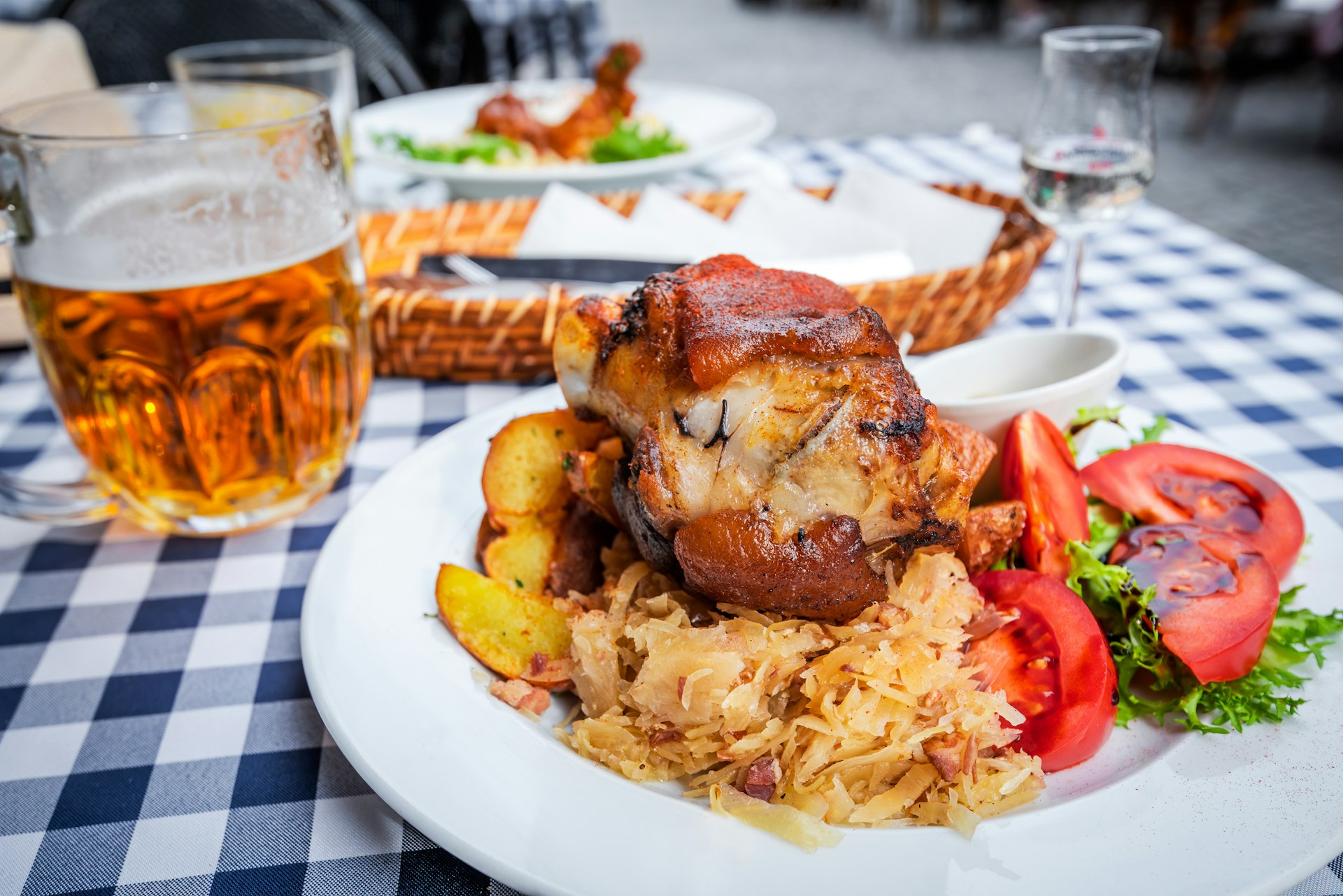 A plate of food with cabbage, salad and potatoes surrounding a huge hunk of pork