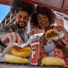 Young friends buying arepas on the city streets from a street vendor.
1503066510