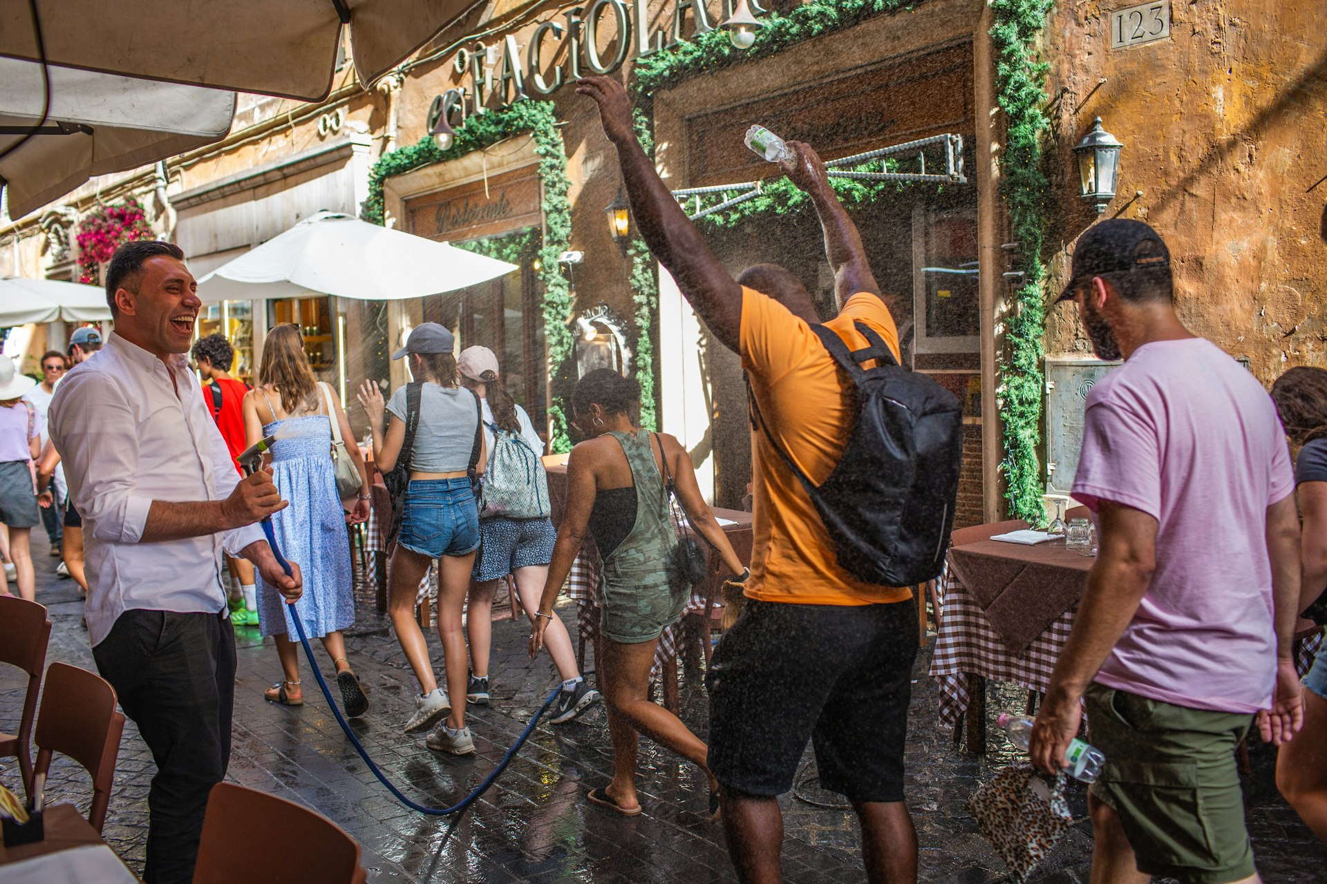 A restaurant employee sprays passersby with a water hose during hot weather caused by the Charon heat wave, in Rome, Italy