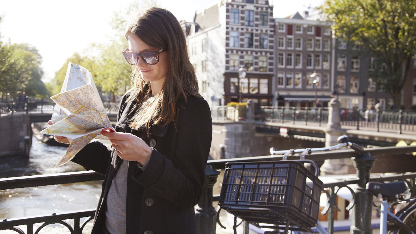 453872967
adventure, direction, travel, finding the way, city life
A woman holding a map next to her bike on a bridge in Amsterdam