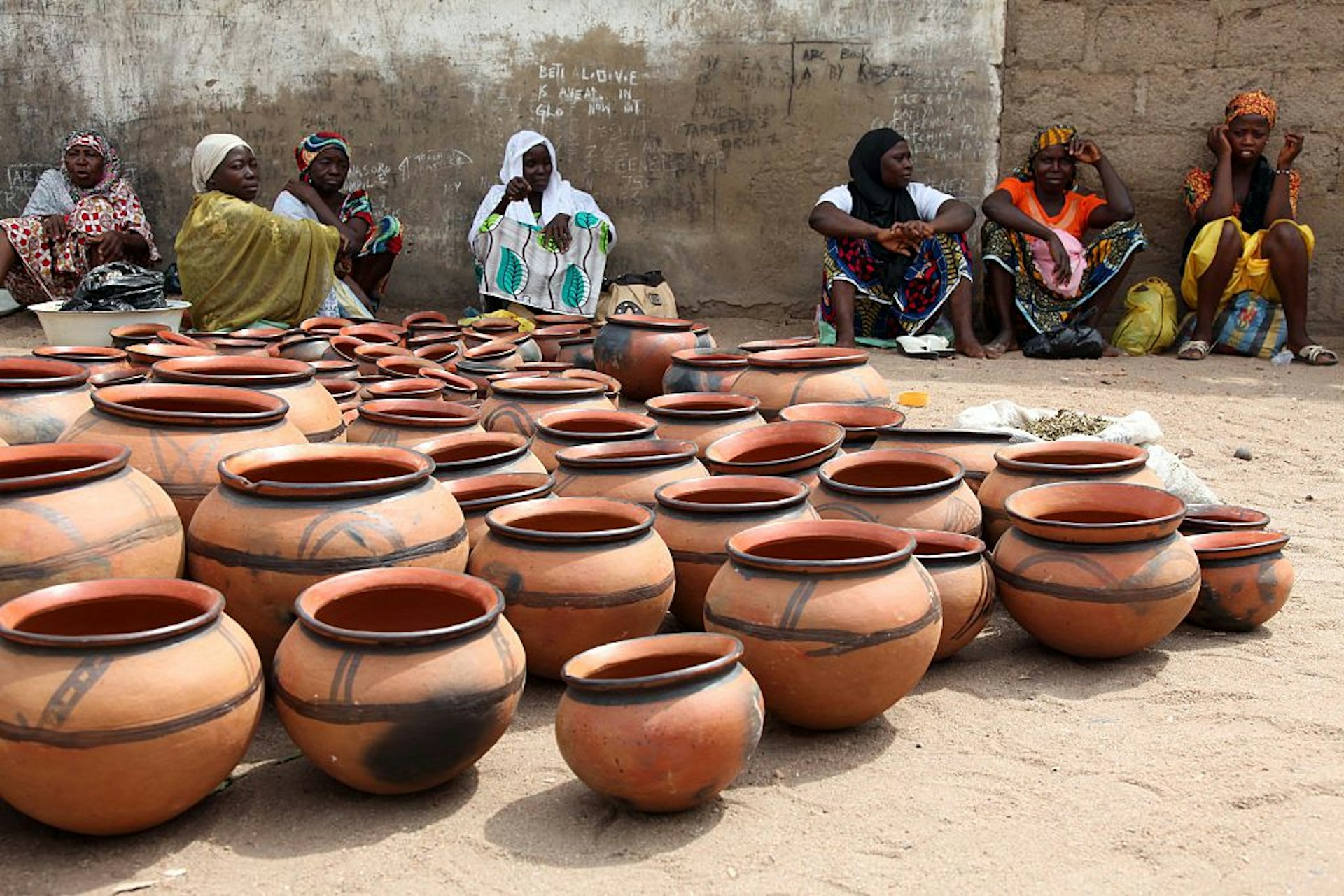 Nigerian women sit next to their pottery which is for sale at the weekly Yola market