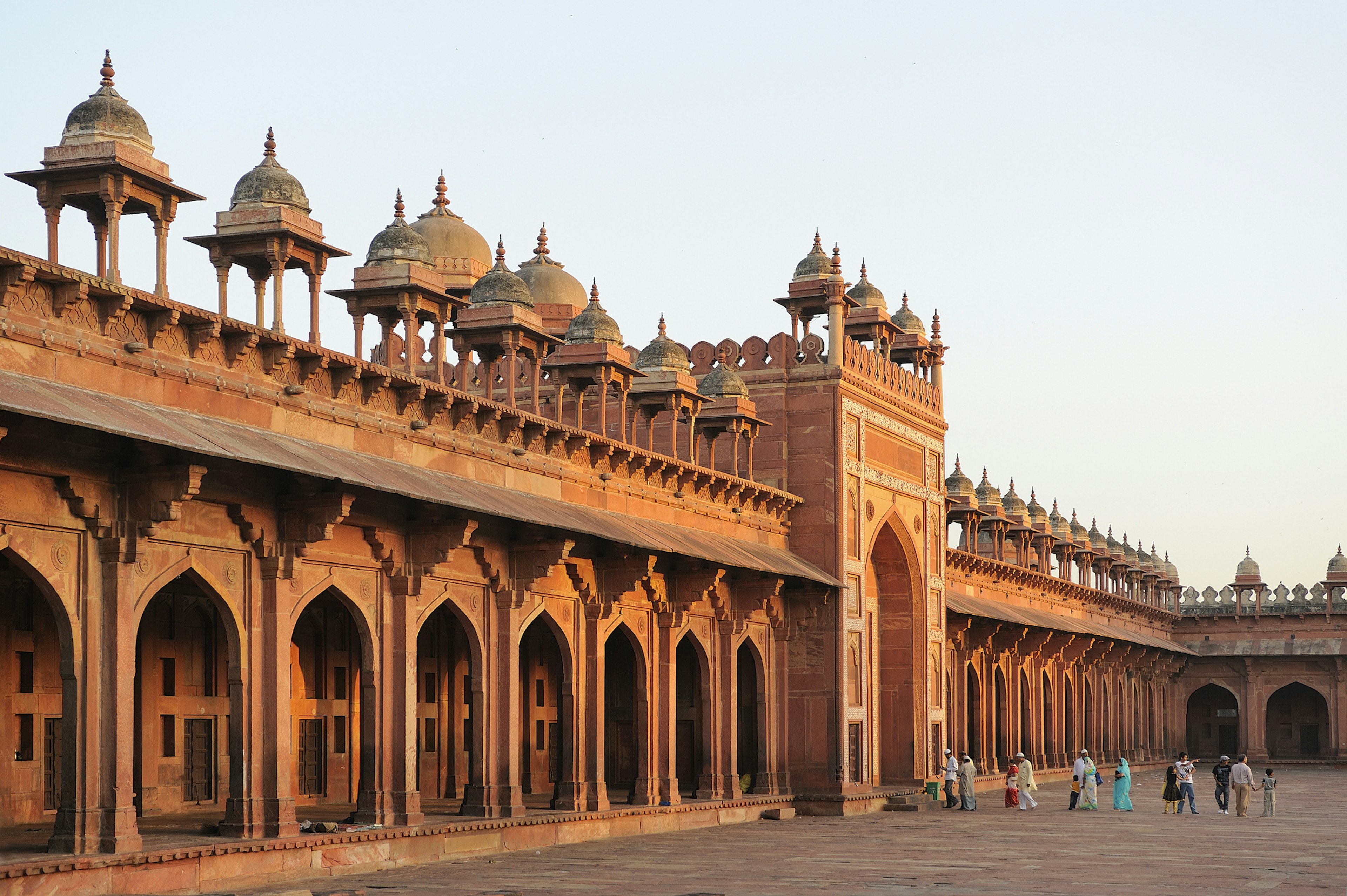 A magnificent red-stone fort with people walking in its gates