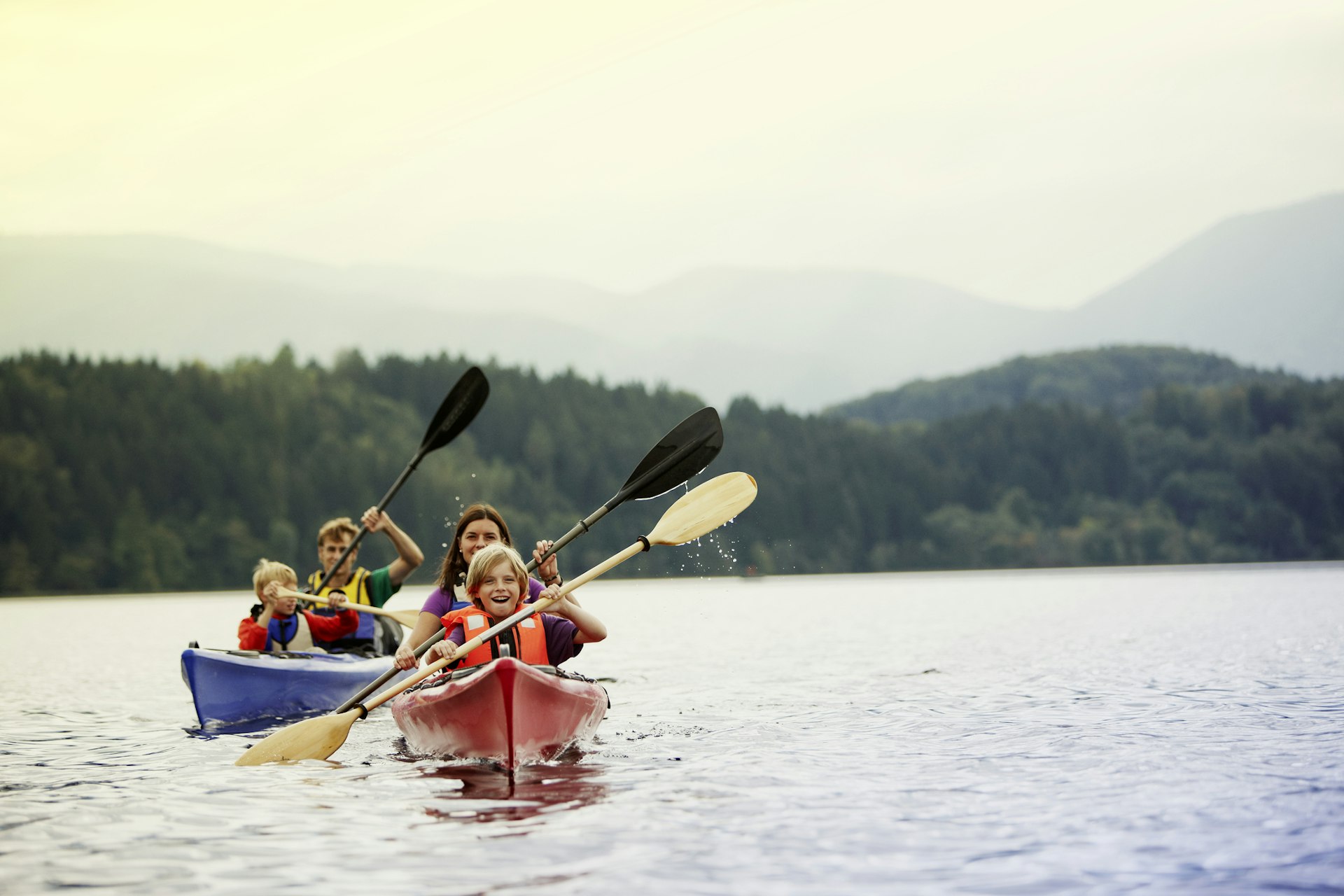 A family of two adults and two young children kayaking on a lake