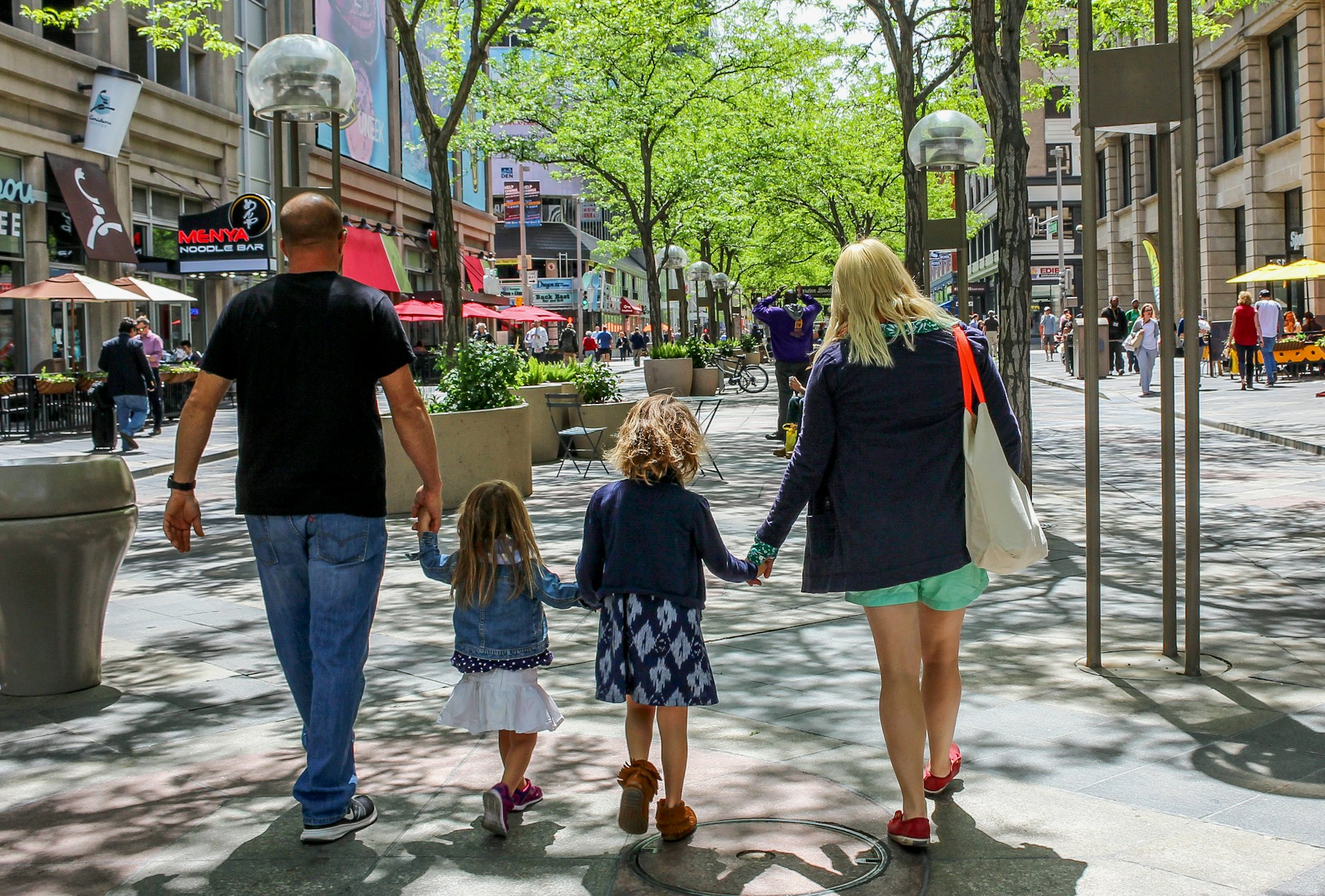 Seen from behind, a family of four walks in downtown Denver 