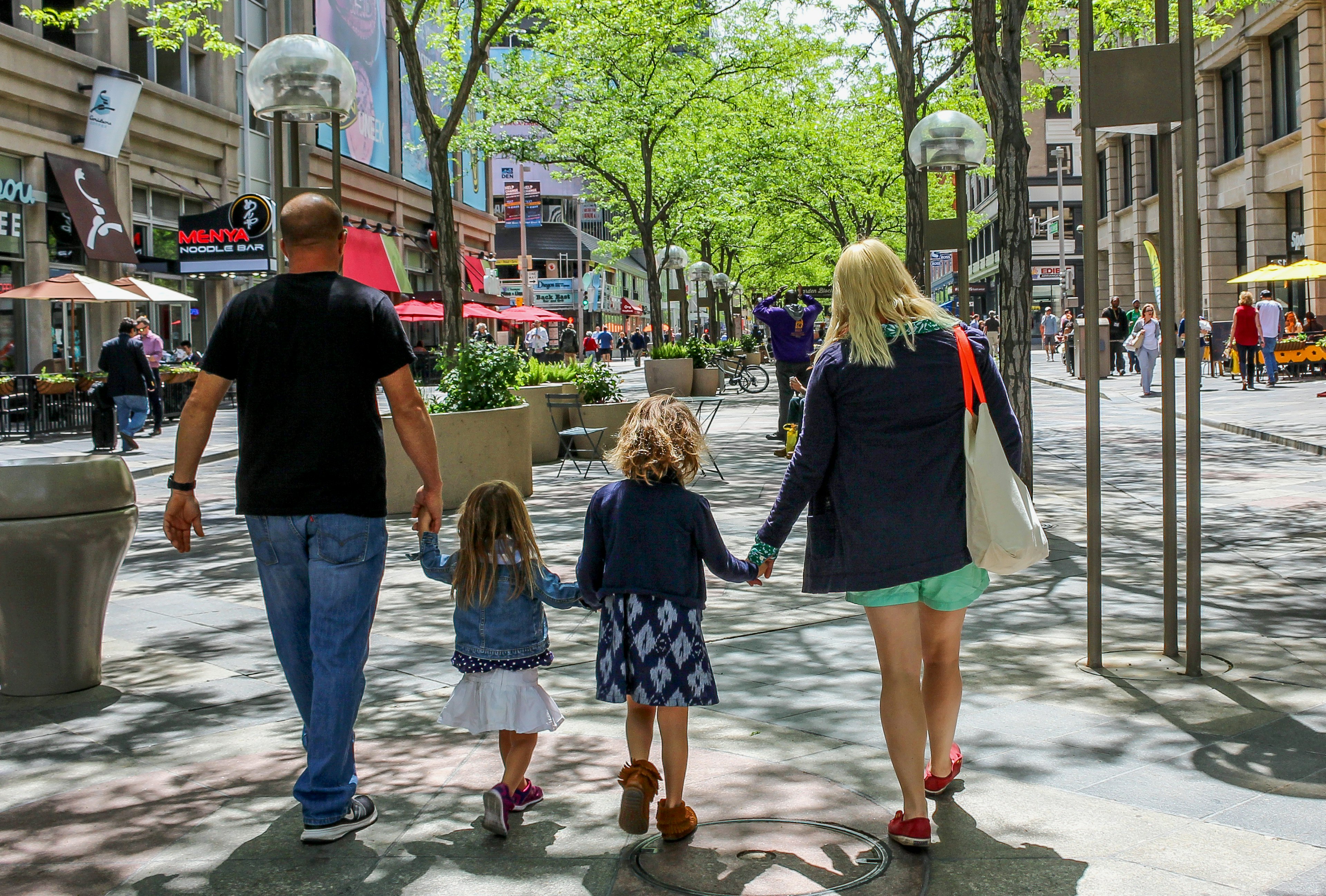 Seen from behind, a family of four walks in downtown Denver