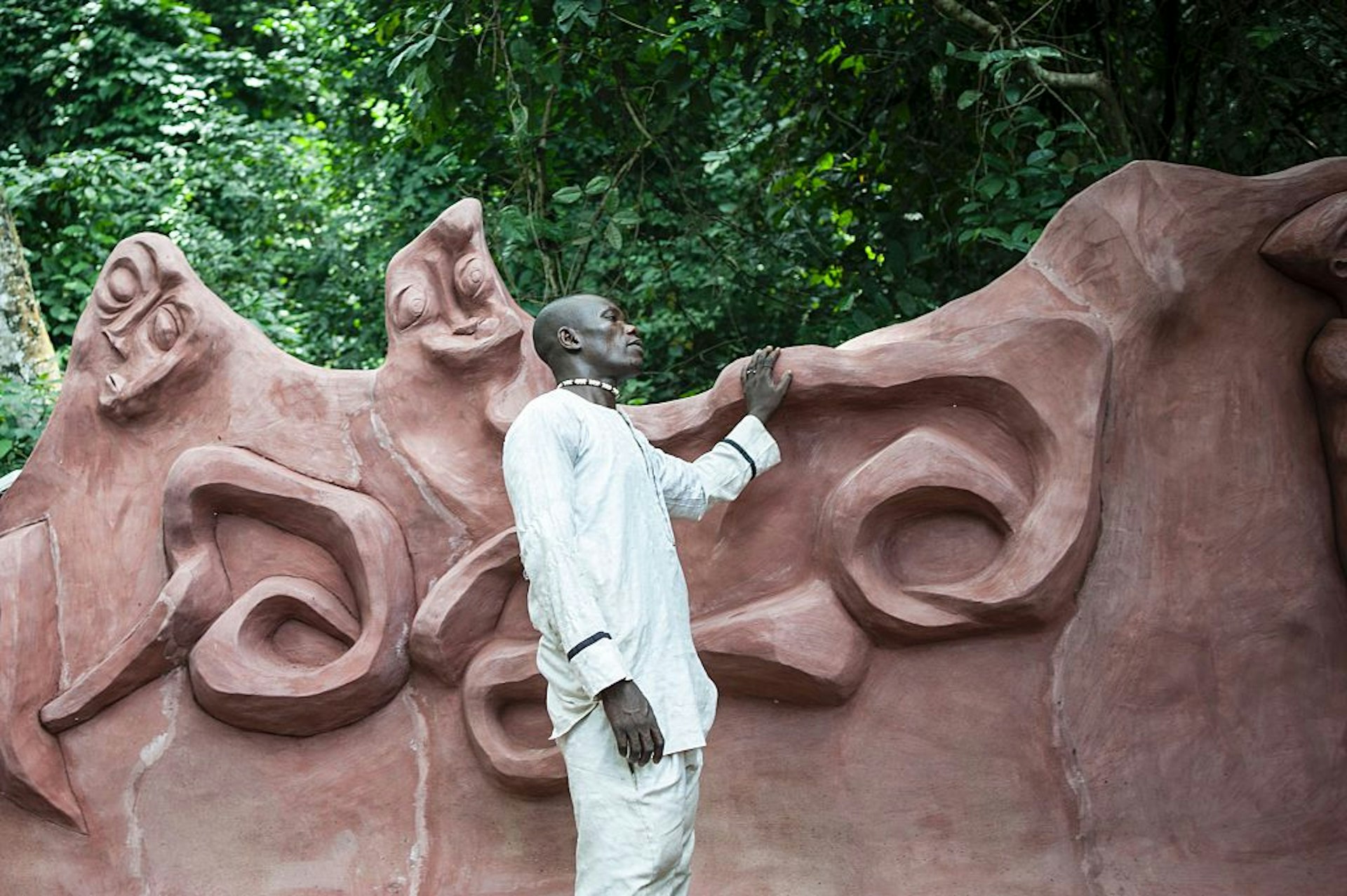 A man stands by a sculpture near the sacred grove during the Osun-Osogbo Festival in Osogbo, Nigeria