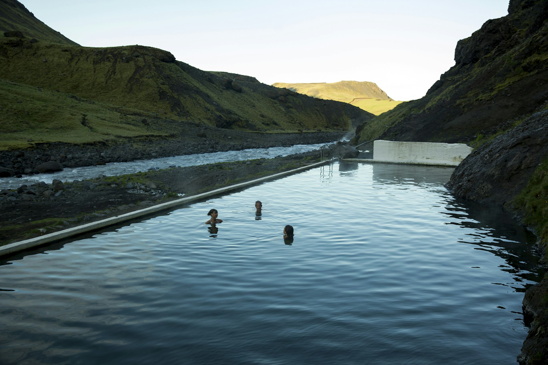 A family swimming in an outdoor pool in Iceland surrounded by rocks