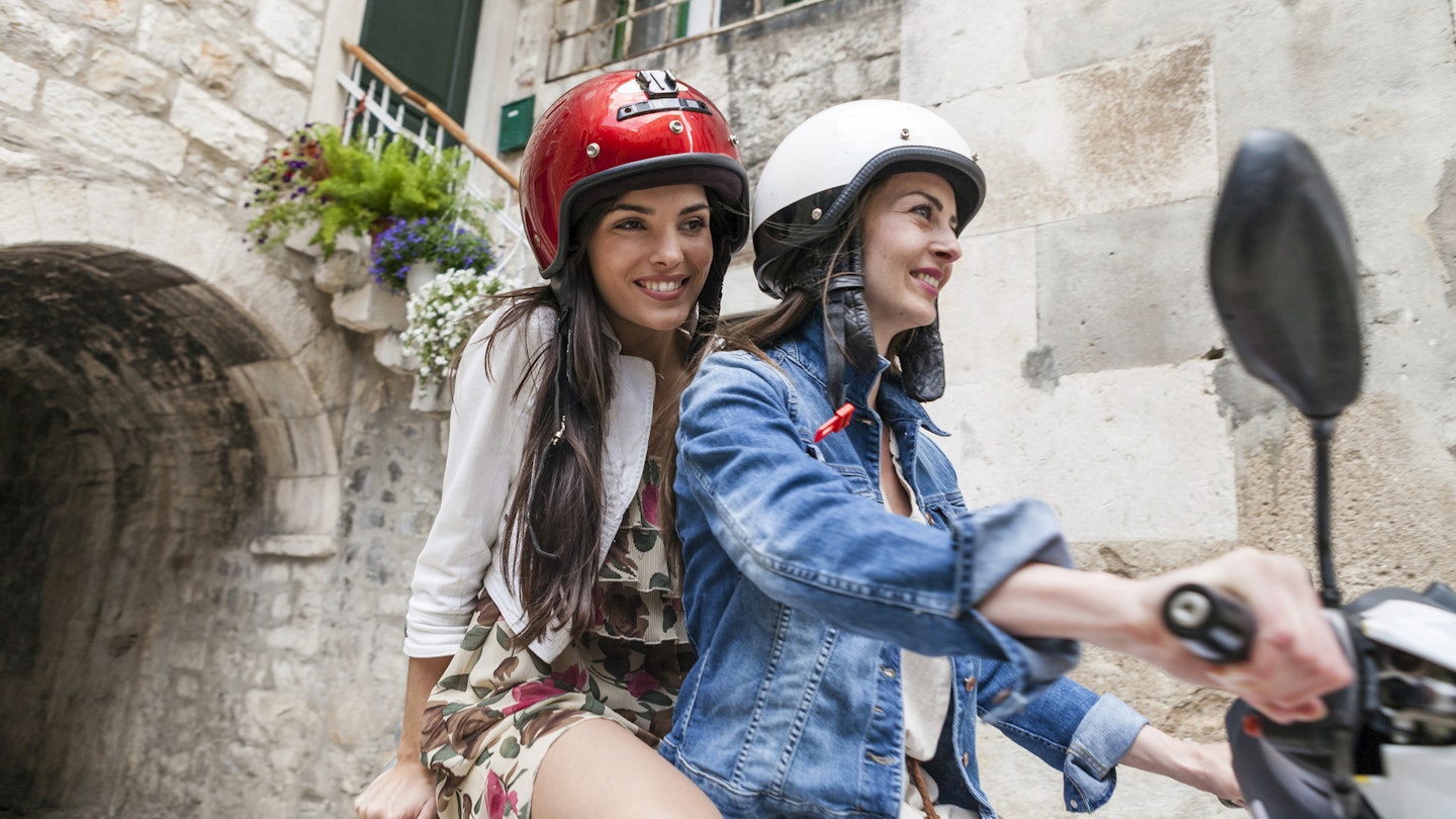 ""
699091621
20 to 24 years, 25 to 29 years, bonding, casual clothing, caucasian ethnicity, crash helmet, croatia, dalmatia, day, denim jacket, dress, feminine, friendship, getting away from it all, happiness, health-and-safety, leisure, lifestyle, moped, on the go, on the road, only female, only young women, outdoors, riding, road trip, sharing, side view, split croatia, summer, three quarter length, togetherness, tourist, traditional, transport, travel destination, two people, village, wearing, young adult, young woman, Split, Dalmatia, Croatia
Two women riding a moped around Split in Croatia