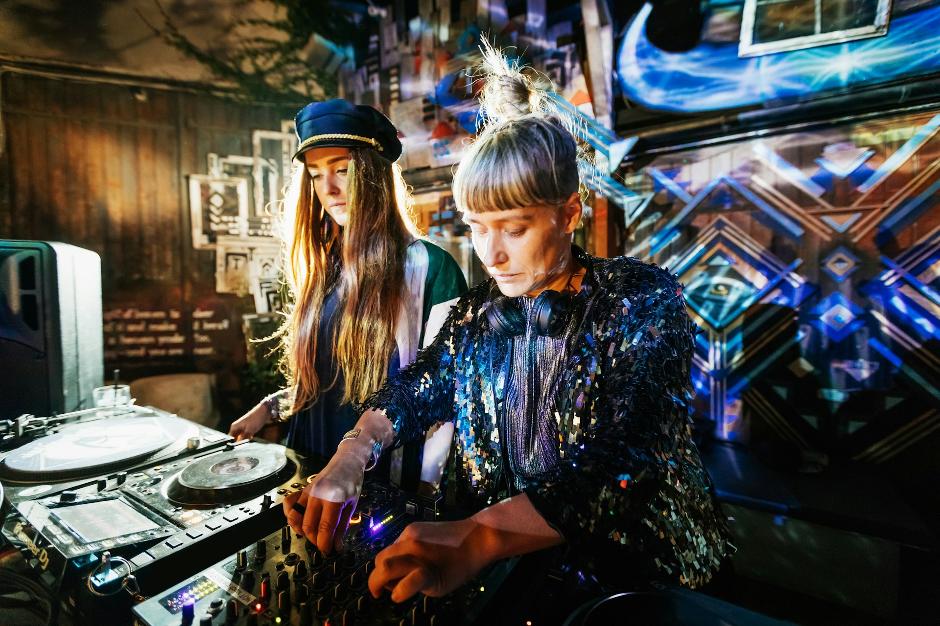 Two stylish DJs performing together late into the night at a colorful outdoor nightclub in Berlin