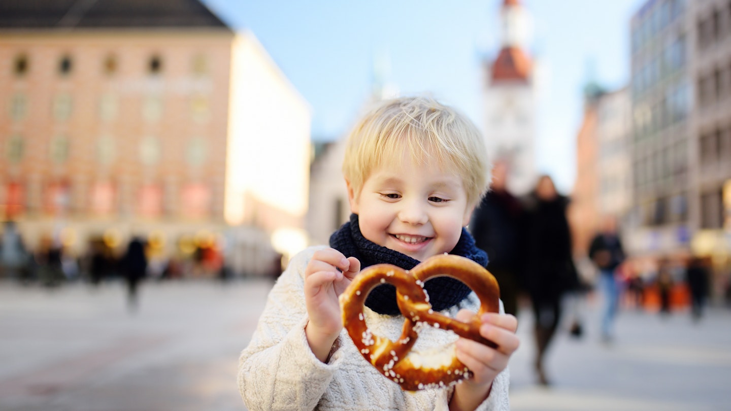 Little tourist holding traditional bavarian bread called pretzel on the town hall building background in Munich, Germany. Preschooler boy enjoy travel with his parents
916654446