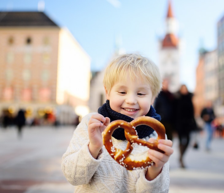 Little tourist holding traditional bavarian bread called pretzel on the town hall building background in Munich, Germany. Preschooler boy enjoy travel with his parents
916654446