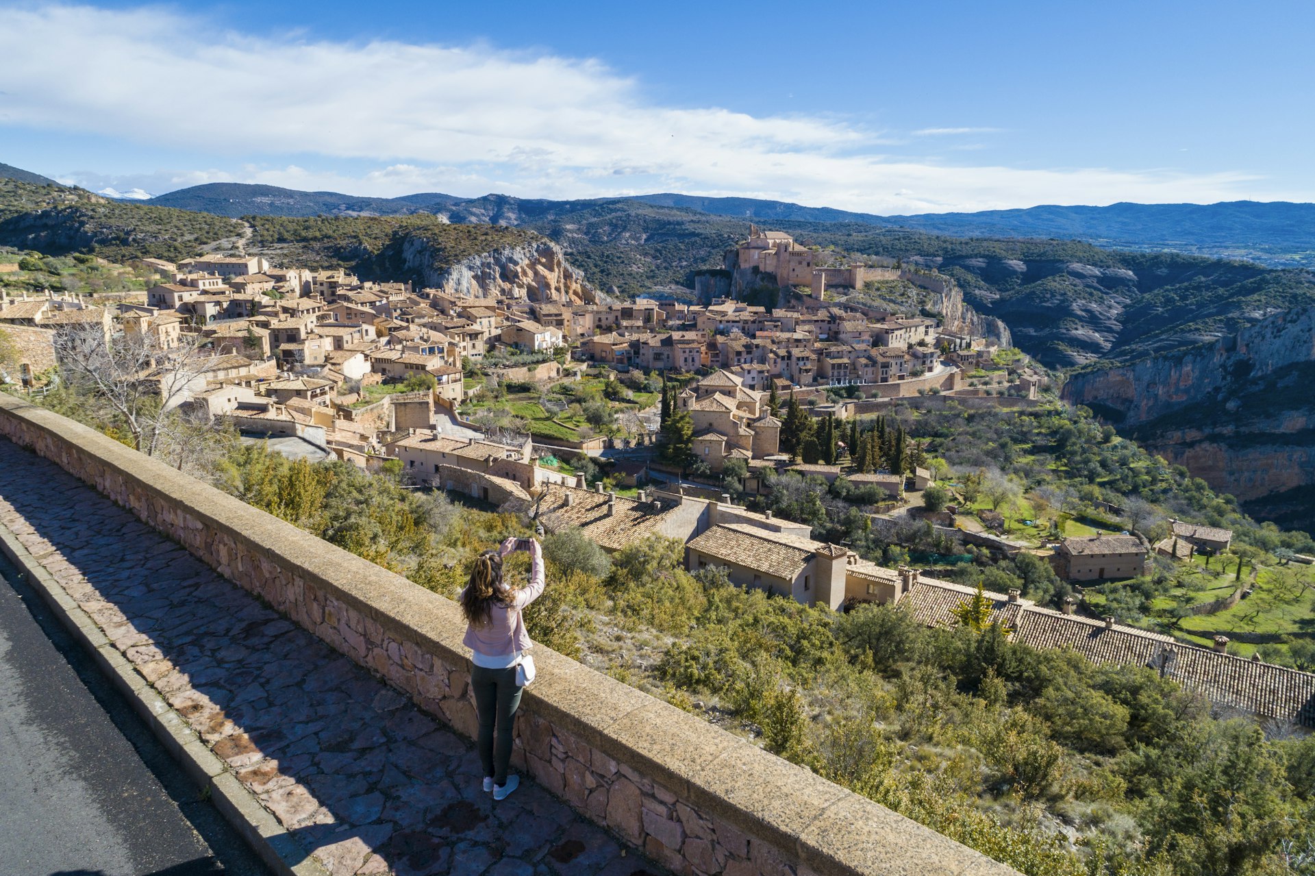 A tourist takes a picture of the hillside Alquezar village in Huesca, Aragon, Spain