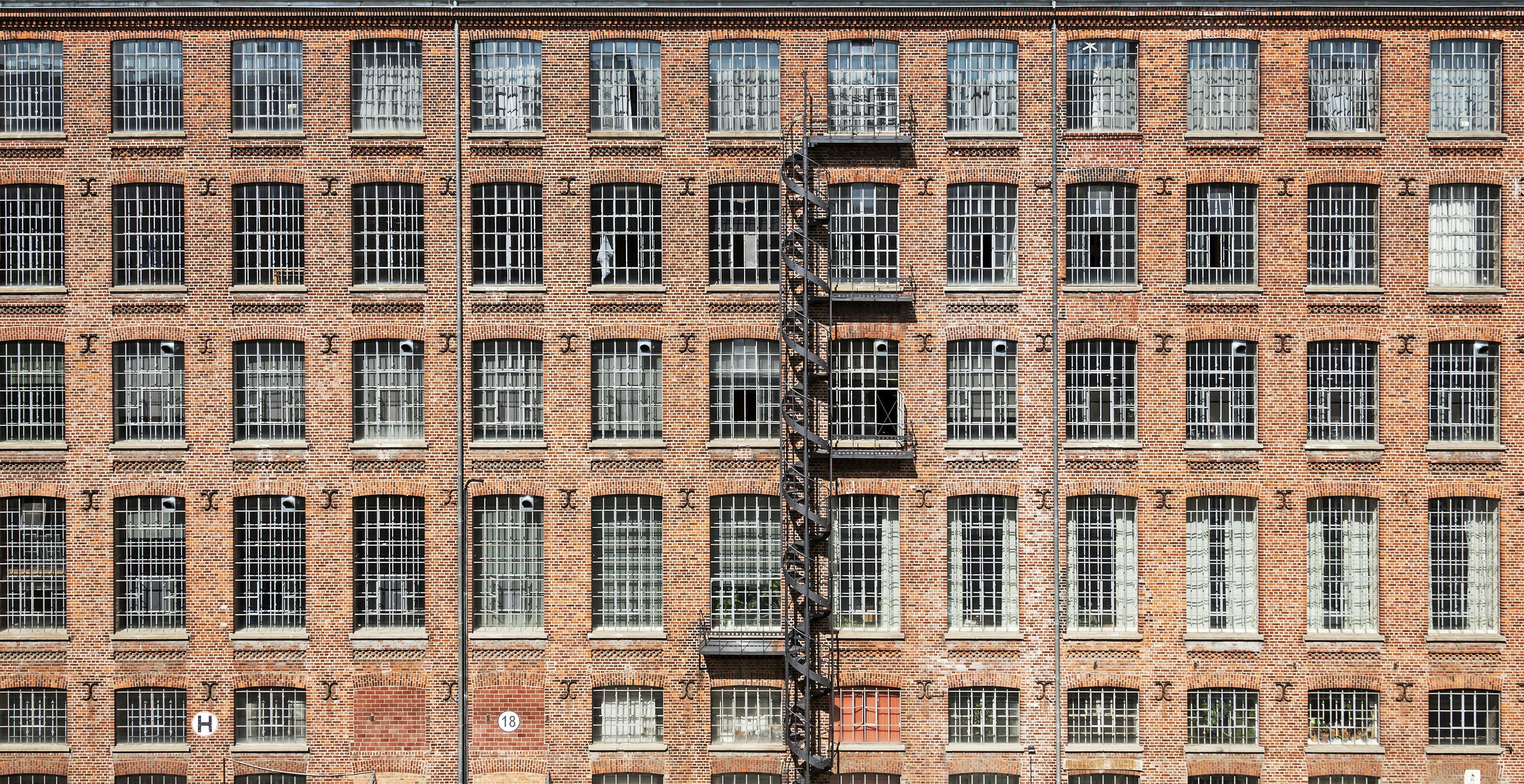 A brick factory building with an exterior spiral staircase