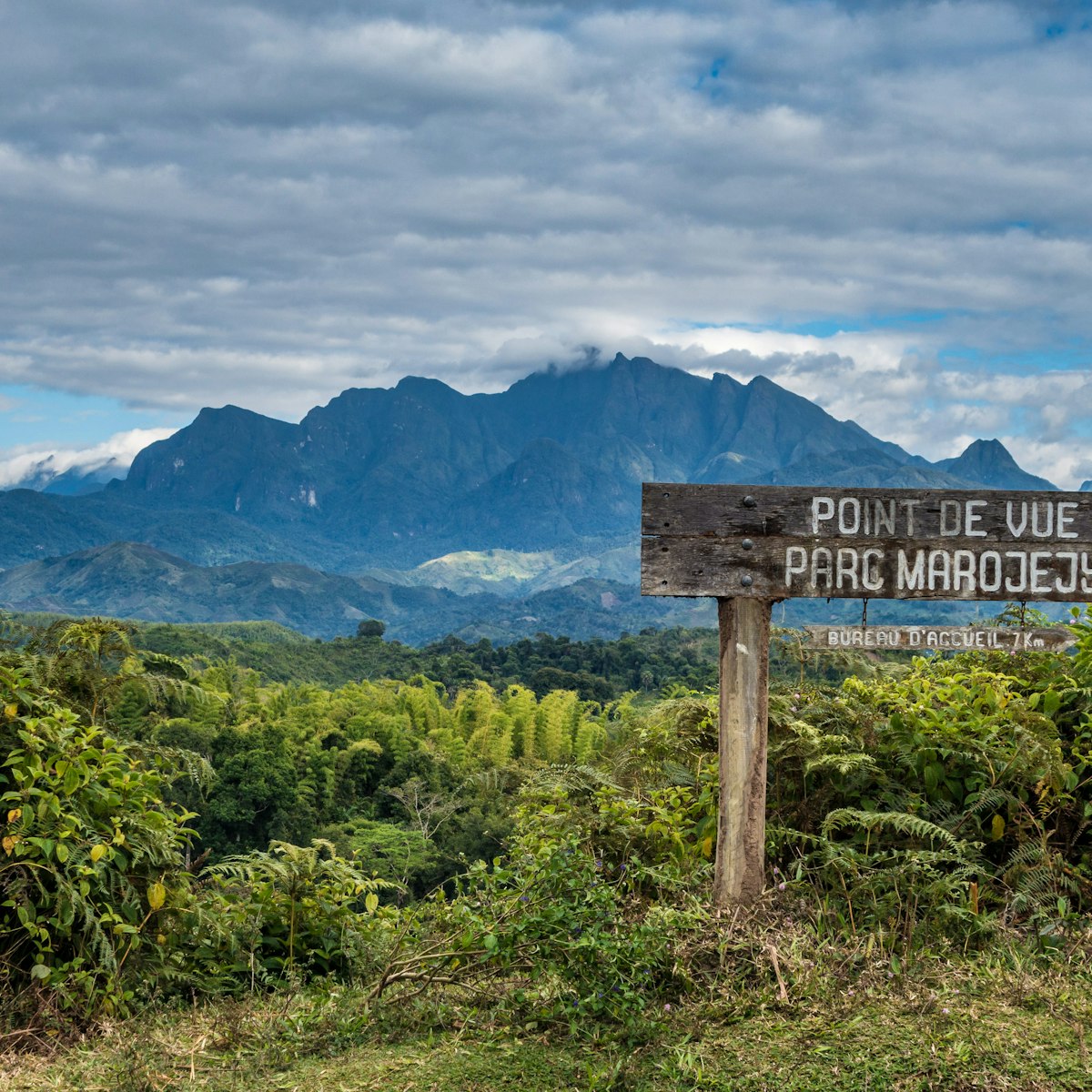 Sign for Marojejy National Park with clouds over mountains.
813983598
Park, Rainforest, Trail, Cliff, Mountain Range, Hill, Marojejy, Sky, Madagascar, Landscape - Scenery, Tree, Forest, Sight, Cloud - Sky, Africa, Summit - Meeting, Natural Parkland, Green Color, Nature, Mountain, Outdoors, Peak, Rock - Object, No People, Horizontal, Photography, Natural, Mountain Peak, Jungle, Grass, Rock, Green, Top, Footpath