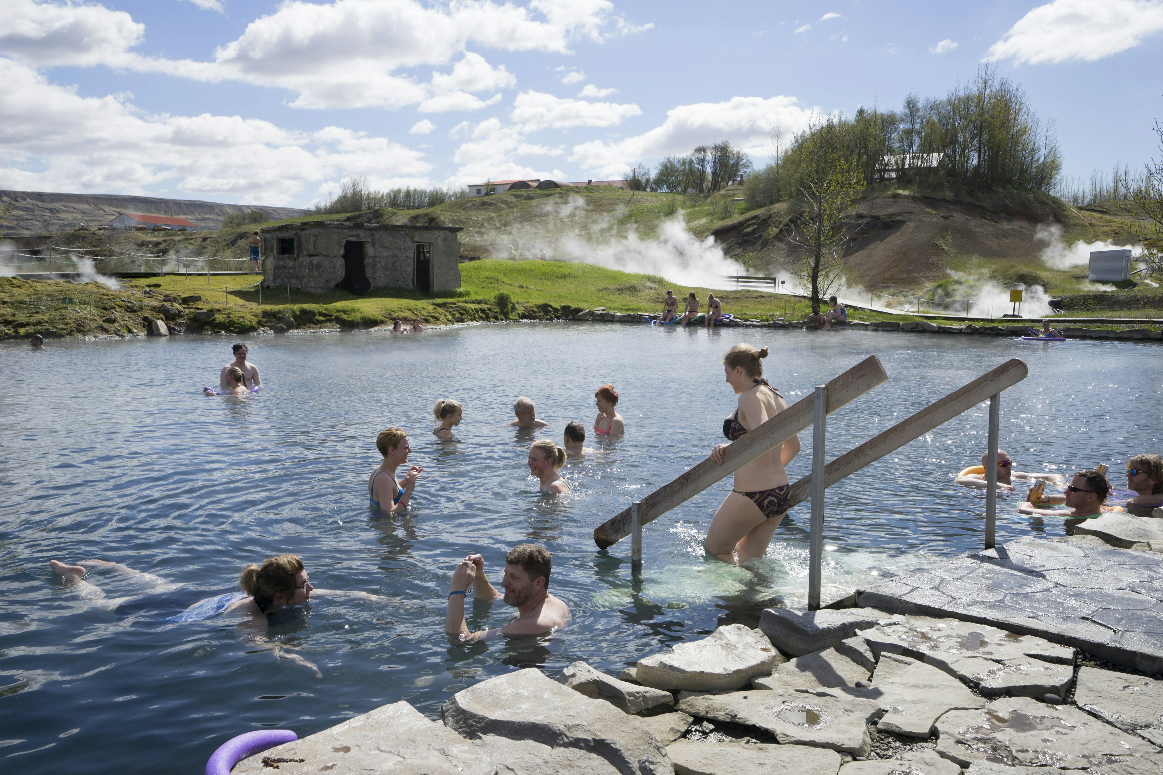 Guests in the geothermal pools at Gamla Laugin on a sunny day.