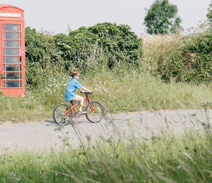 Boy Riding Bicycle In English Countryside
Boy cycling in English countryside past traditional British telephone box.