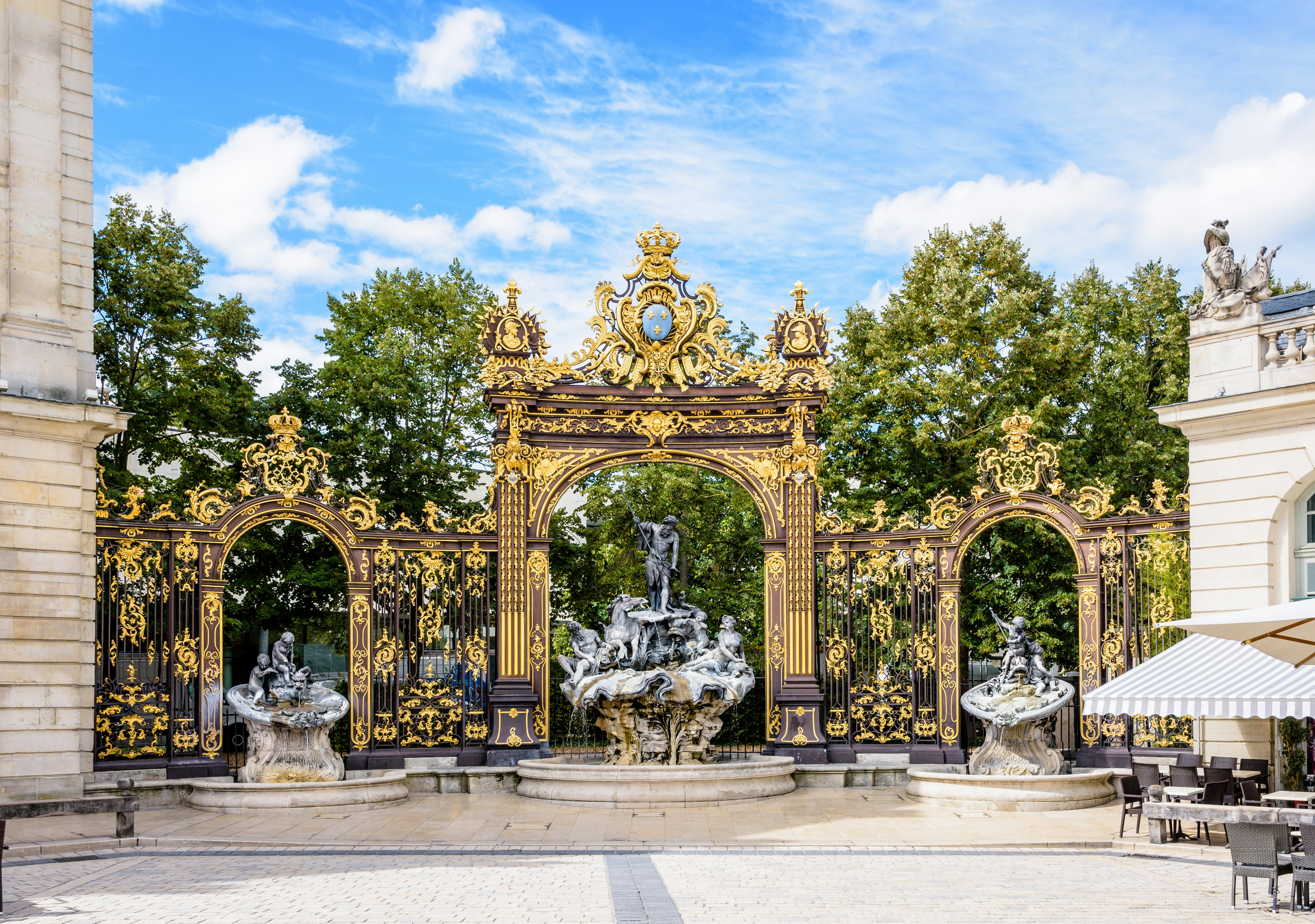 The fountain of Neptune in the Rococo style and the gilded wrought iron portico in the north-west corner of the place Stanislas in Nancy, France.
