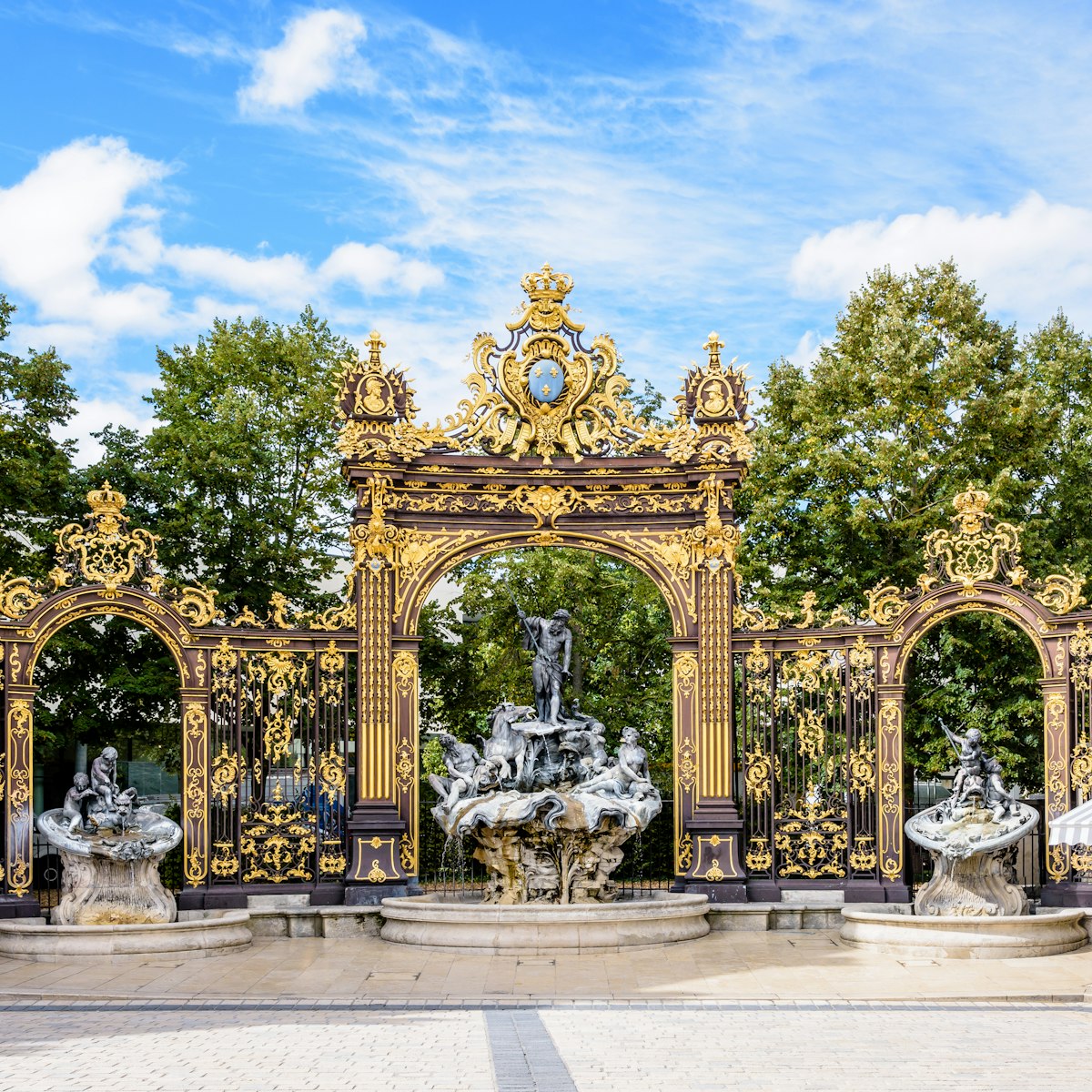 The fountain of Neptune in the Rococo style and the gilded wrought iron portico in the north-west corner of the place Stanislas in Nancy, France.