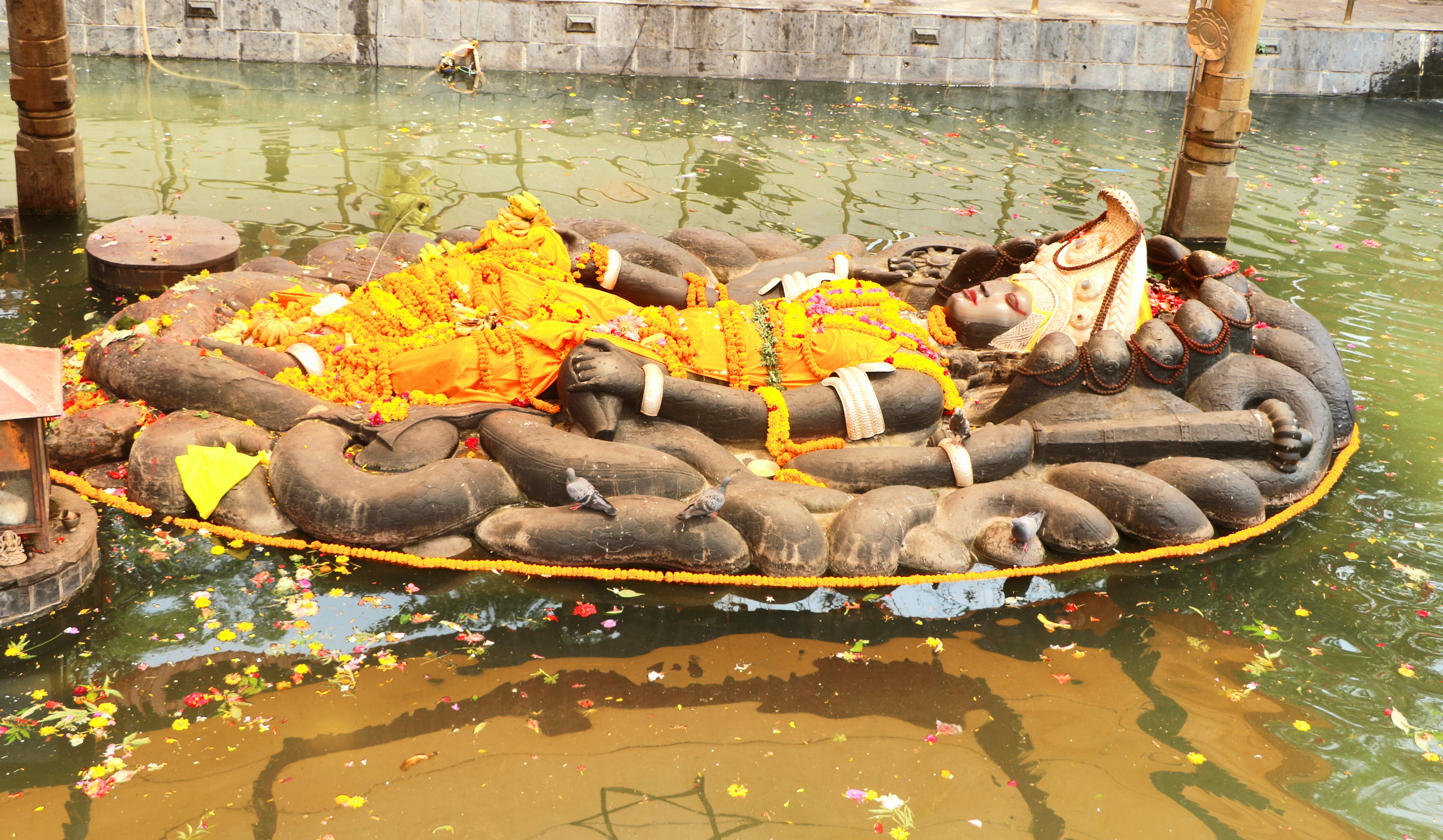 The Budhanilkantha statue of the Hindu god Vishnu, lies in a reclining position inside a recessed tank of water.