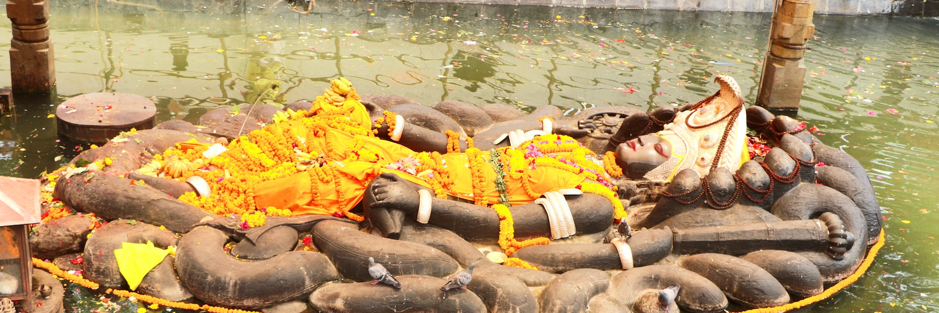 The Budhanilkantha statue of the Hindu god Vishnu, lies in a reclining position inside a recessed tank of water.