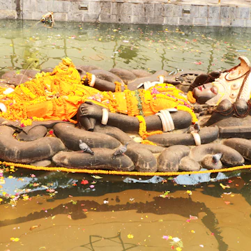 The Budhanilkantha statue of the Hindu god Vishnu, lies in a reclining position inside a recessed tank of water.