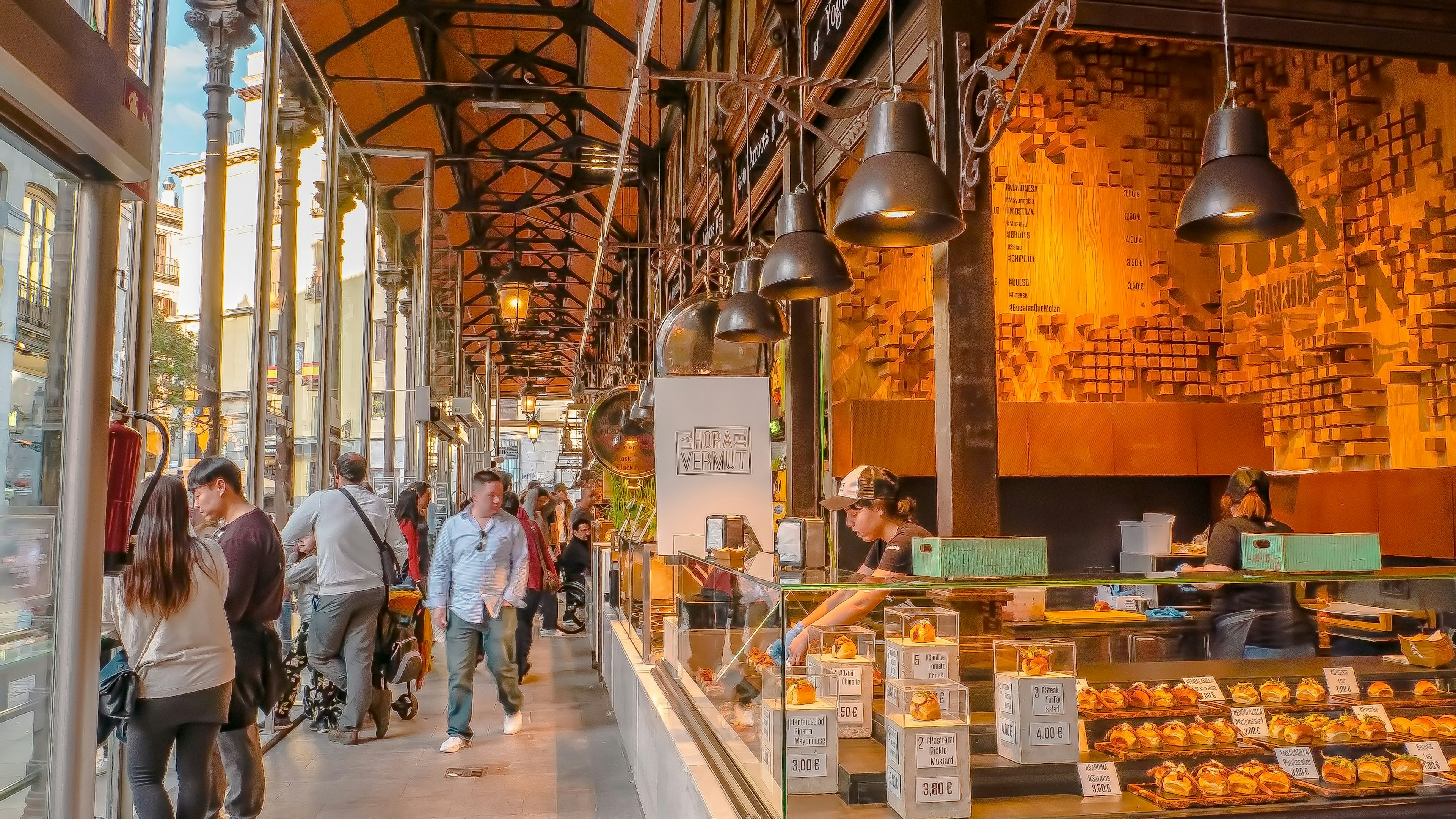 A covered market building with lots of people visiting food stalls