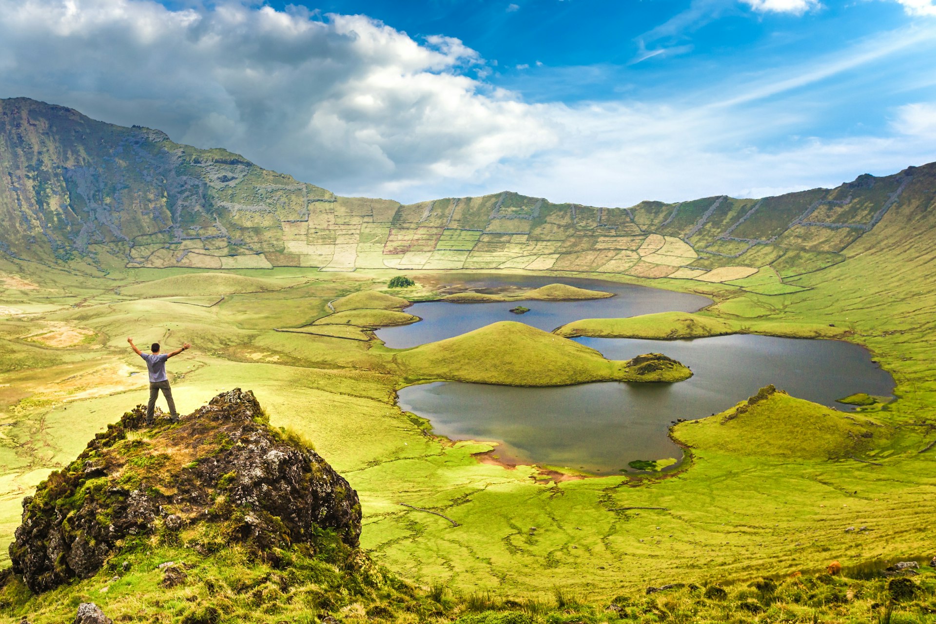 A man opens his arms looking at the Caldeirão, Covro, the Azores, Portugal