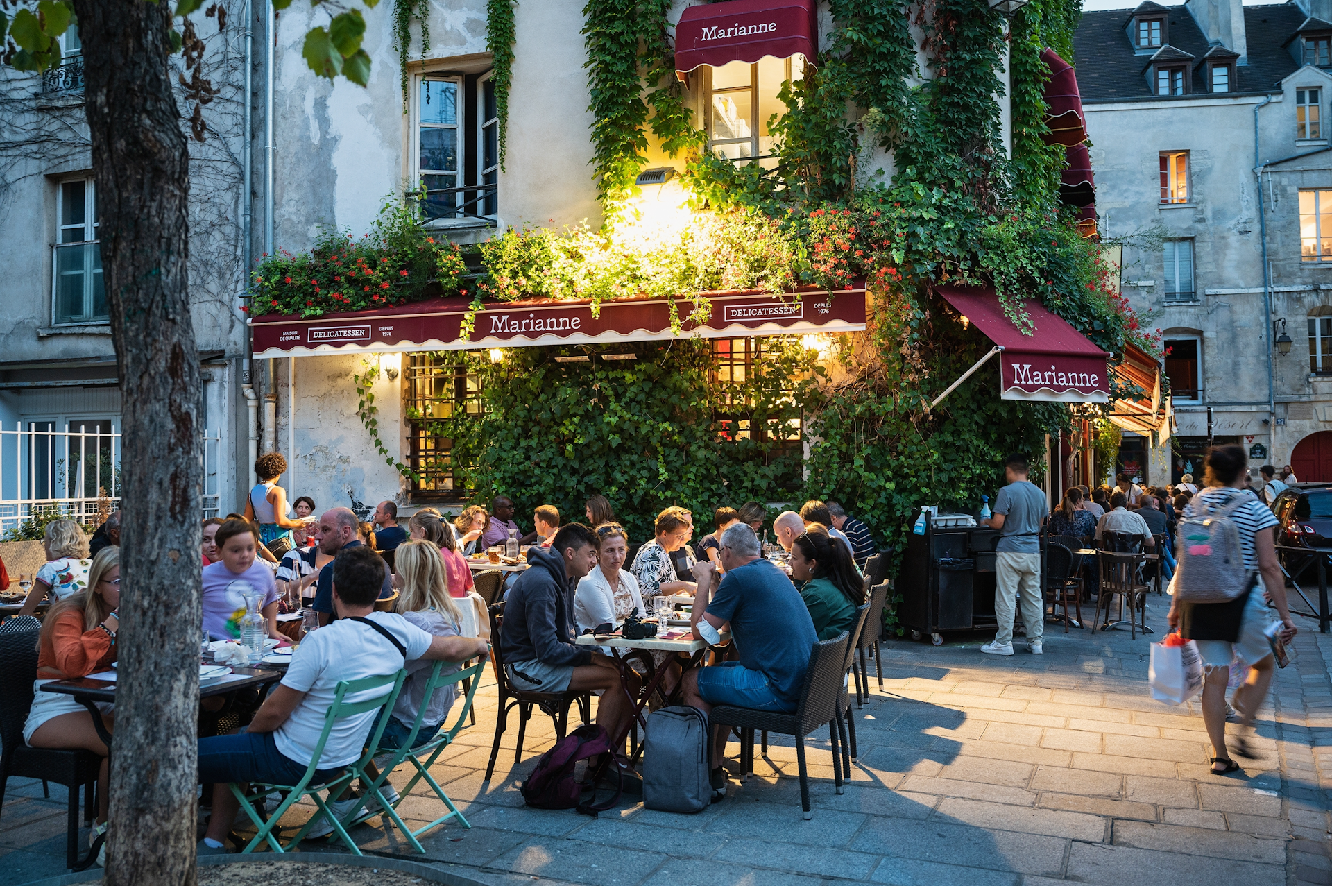 People dining at outdoor terraces during an evening in the Marais neighborhood Paris