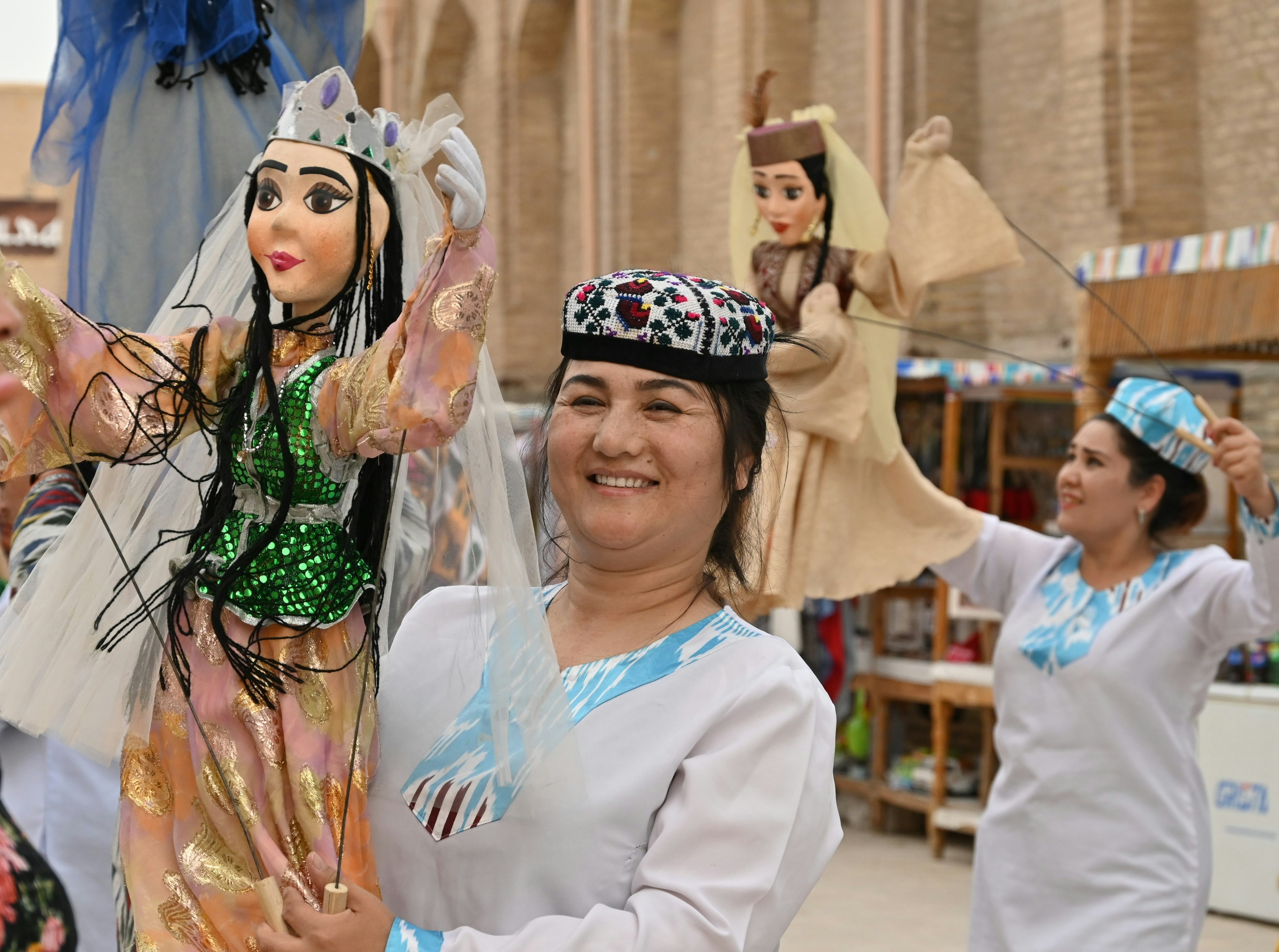 A couple of puppeteers perform with large puppets in the street of a city