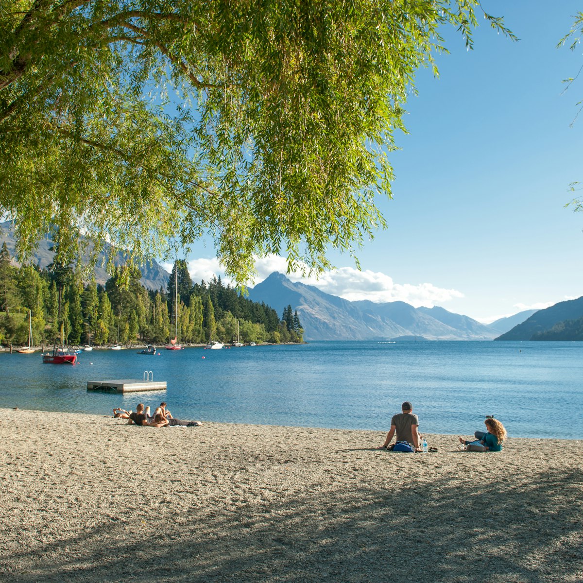 Tourists relax at the shore of Lake Wakatipu in Queenstown.