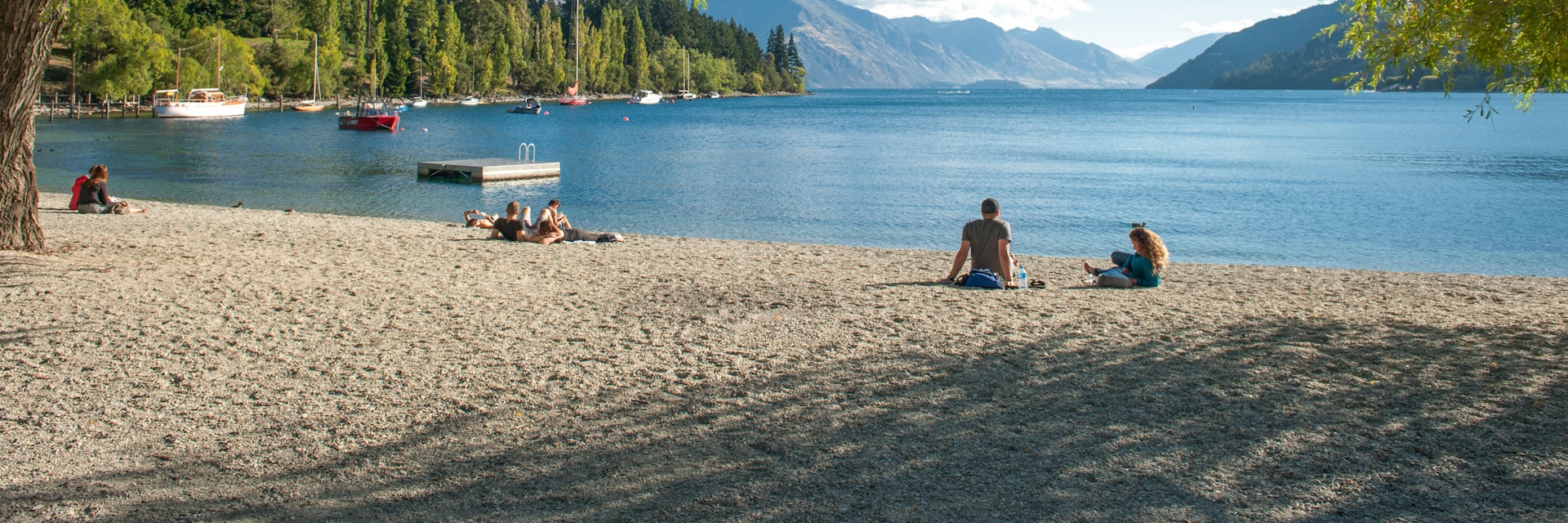 Tourists relax at the shore of Lake Wakatipu in Queenstown.