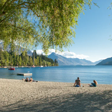 Tourists relax at the shore of Lake Wakatipu in Queenstown.