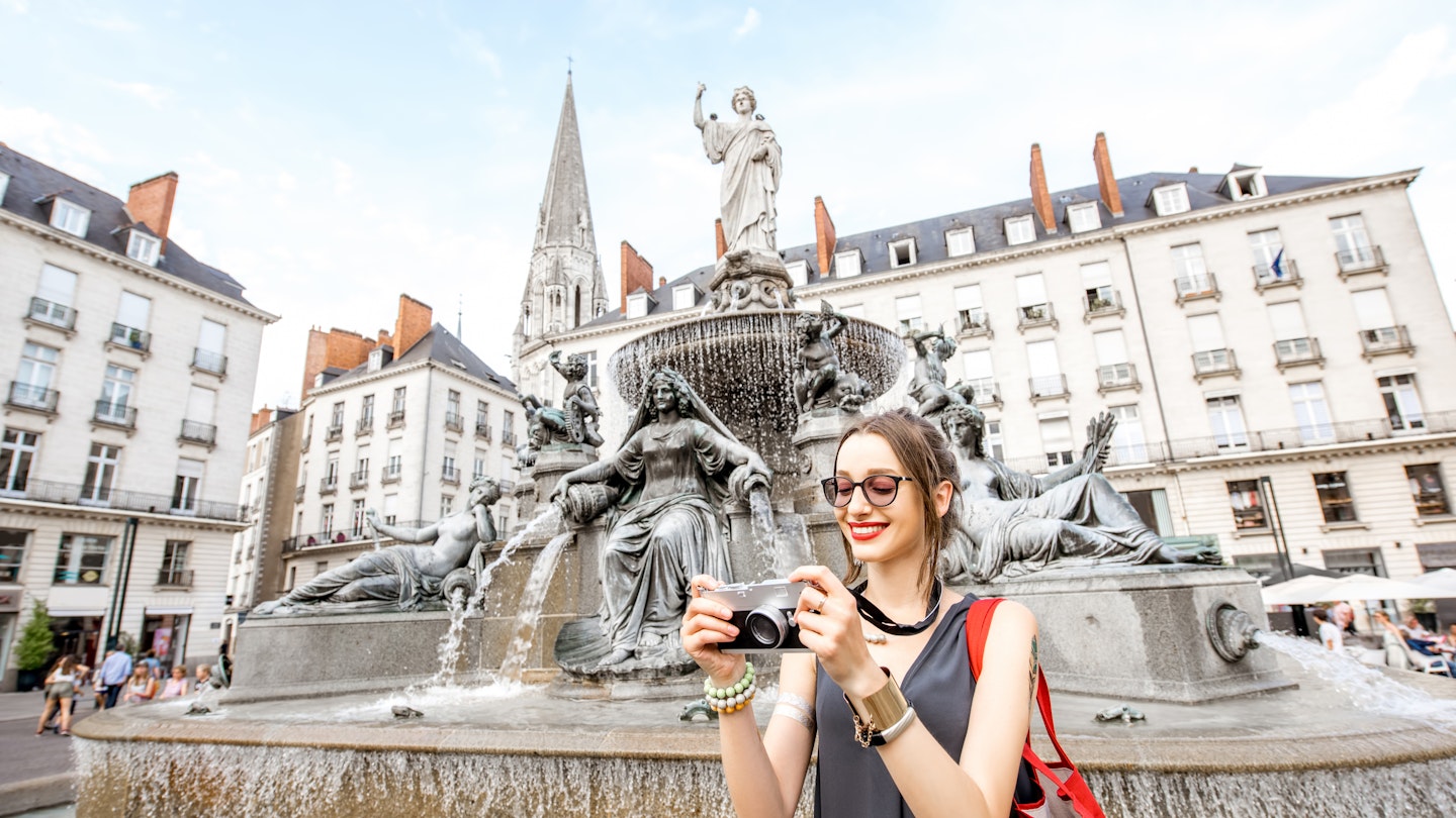 Young and happy woman tourist with photo camera standing near the fountain on the Royal square in Nantes city, France; Shutterstock ID 673491862; purchase_order: 65050 / online editorial / nantes first time; job: ; client: ; other:
673491862