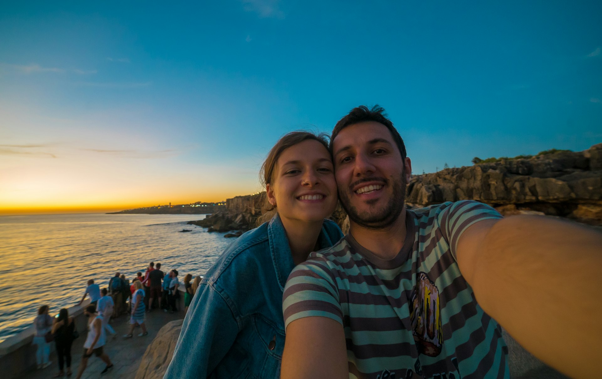 A happy couple taking selfie in Cascais, Portugal during sunset
