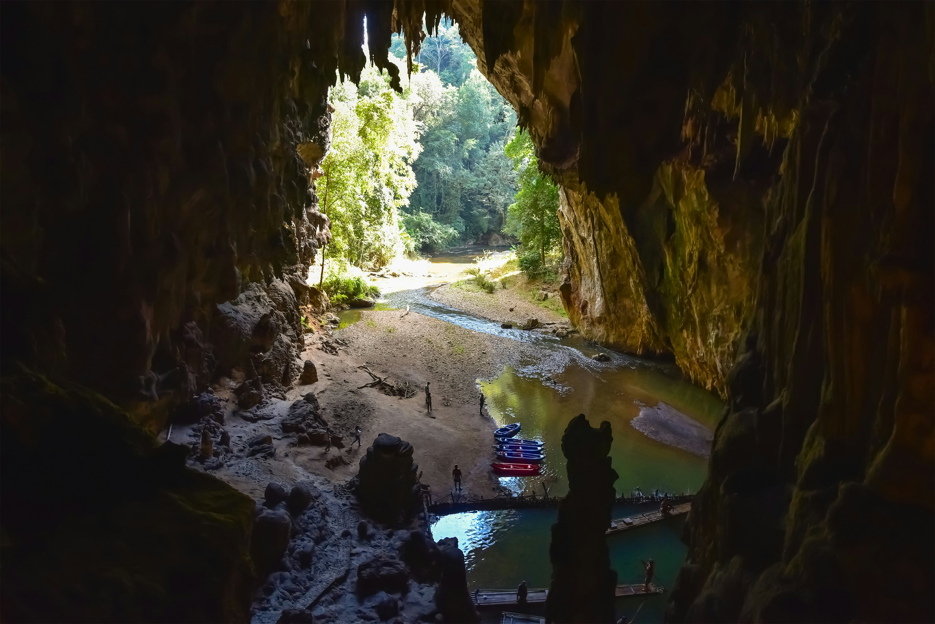 A stalactite cave with kayaks in the small creek