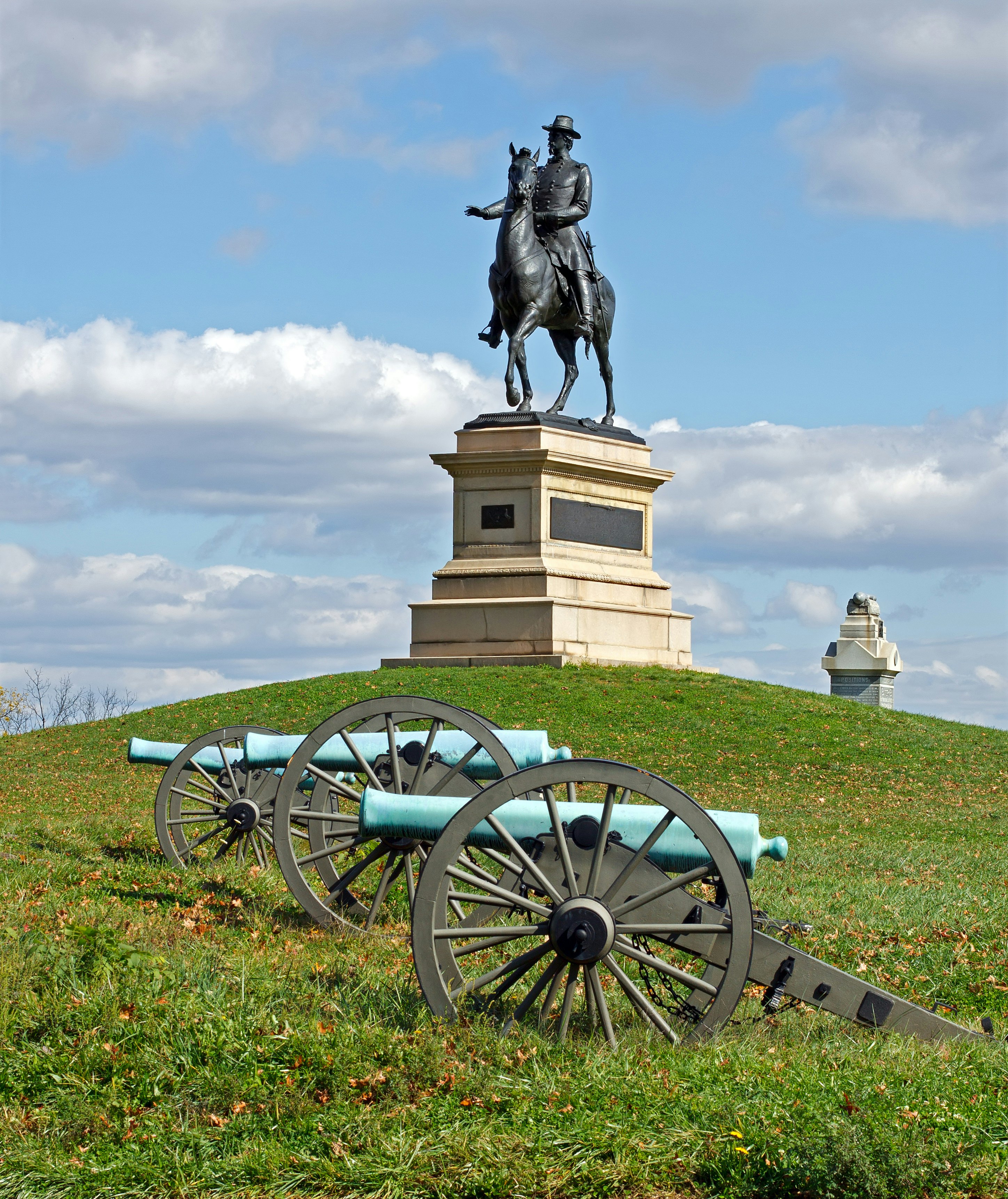 A Gettysburg statue with military wagons in the forefront