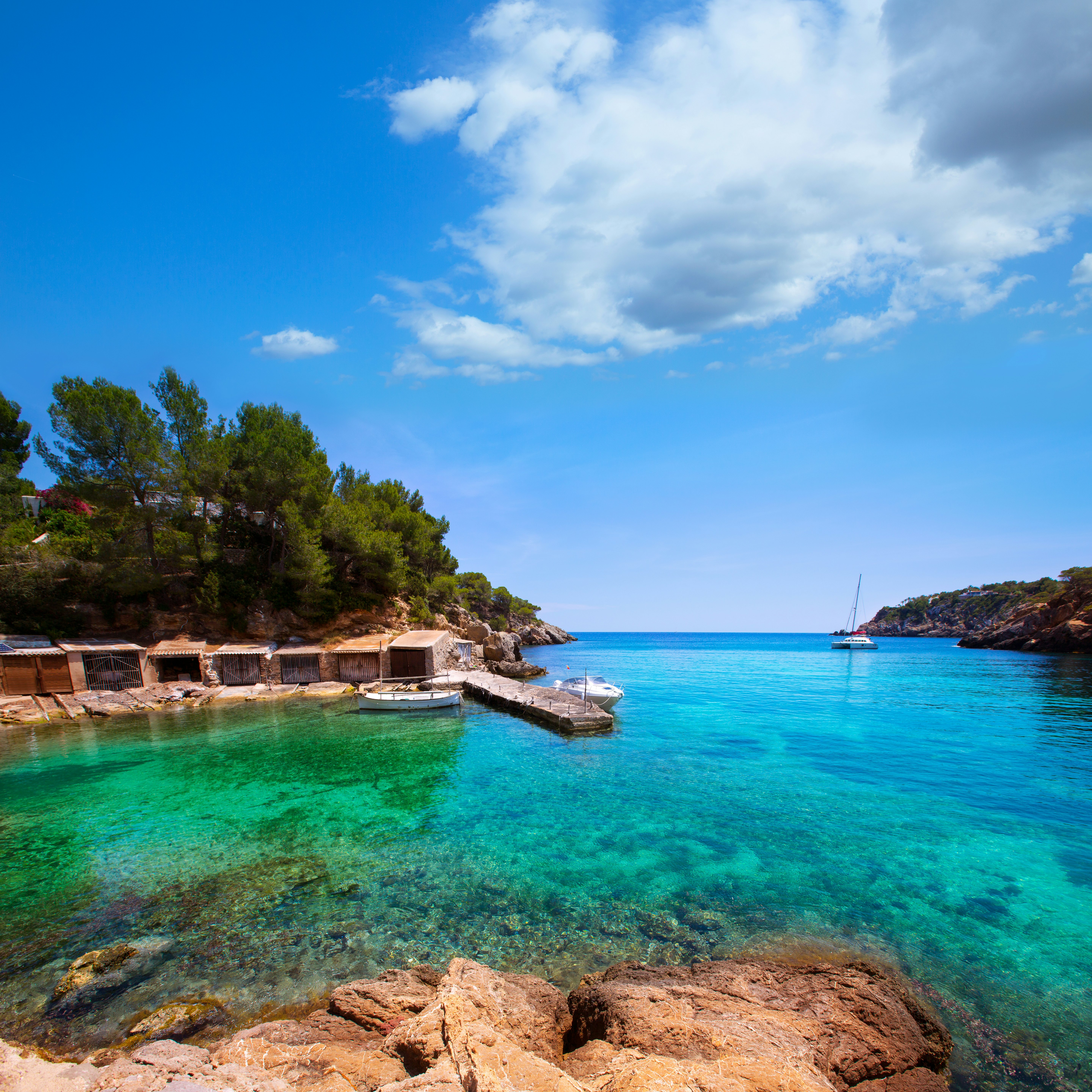 Boats docked in the turquoise waters of Cala Mestella.